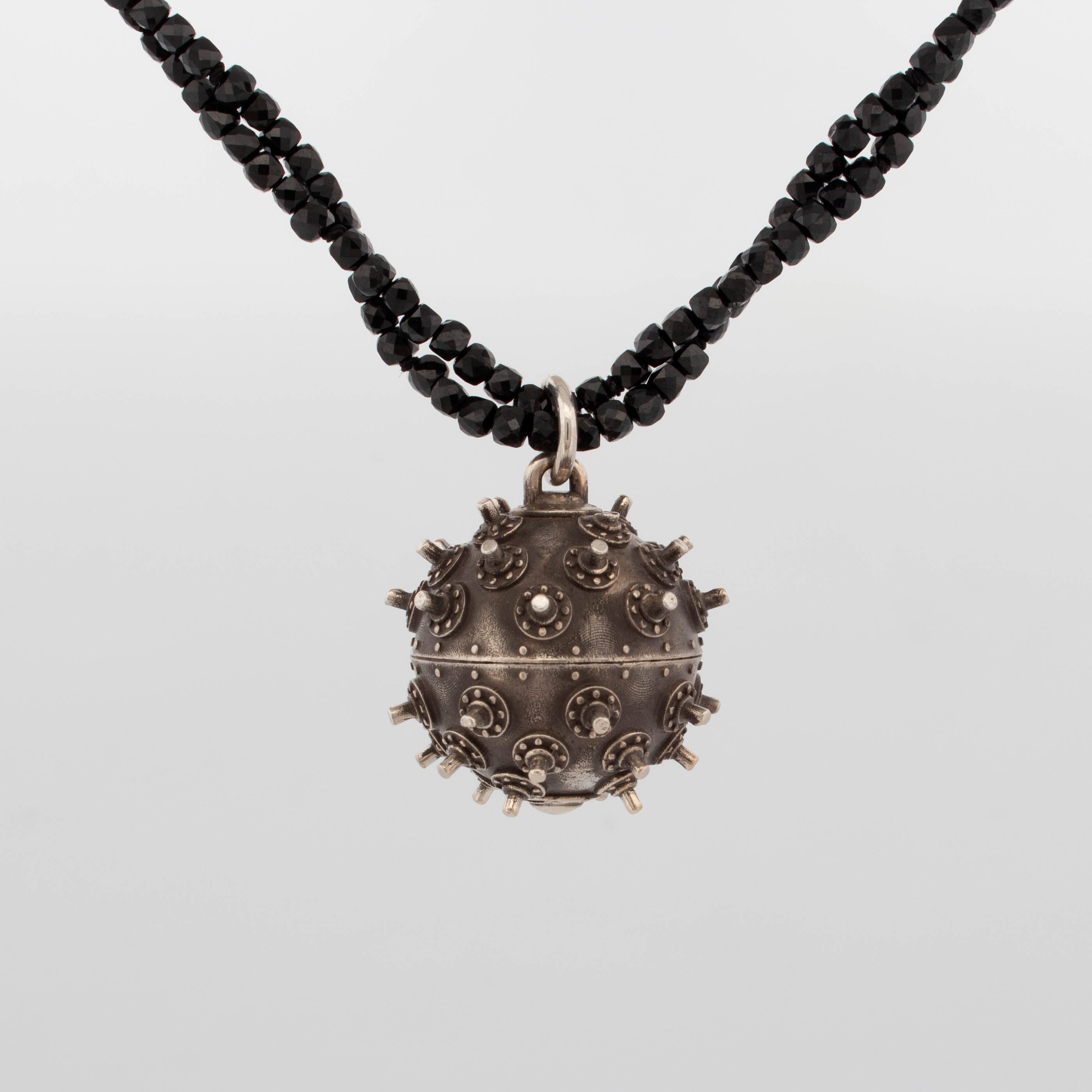 Sterling silver deep sea mine pendant with oxidised finish and spiked rivet detailing, suspended from a double strand of faceted black spinel beads; handcrafted statement necklace with industrial and maritime influence.