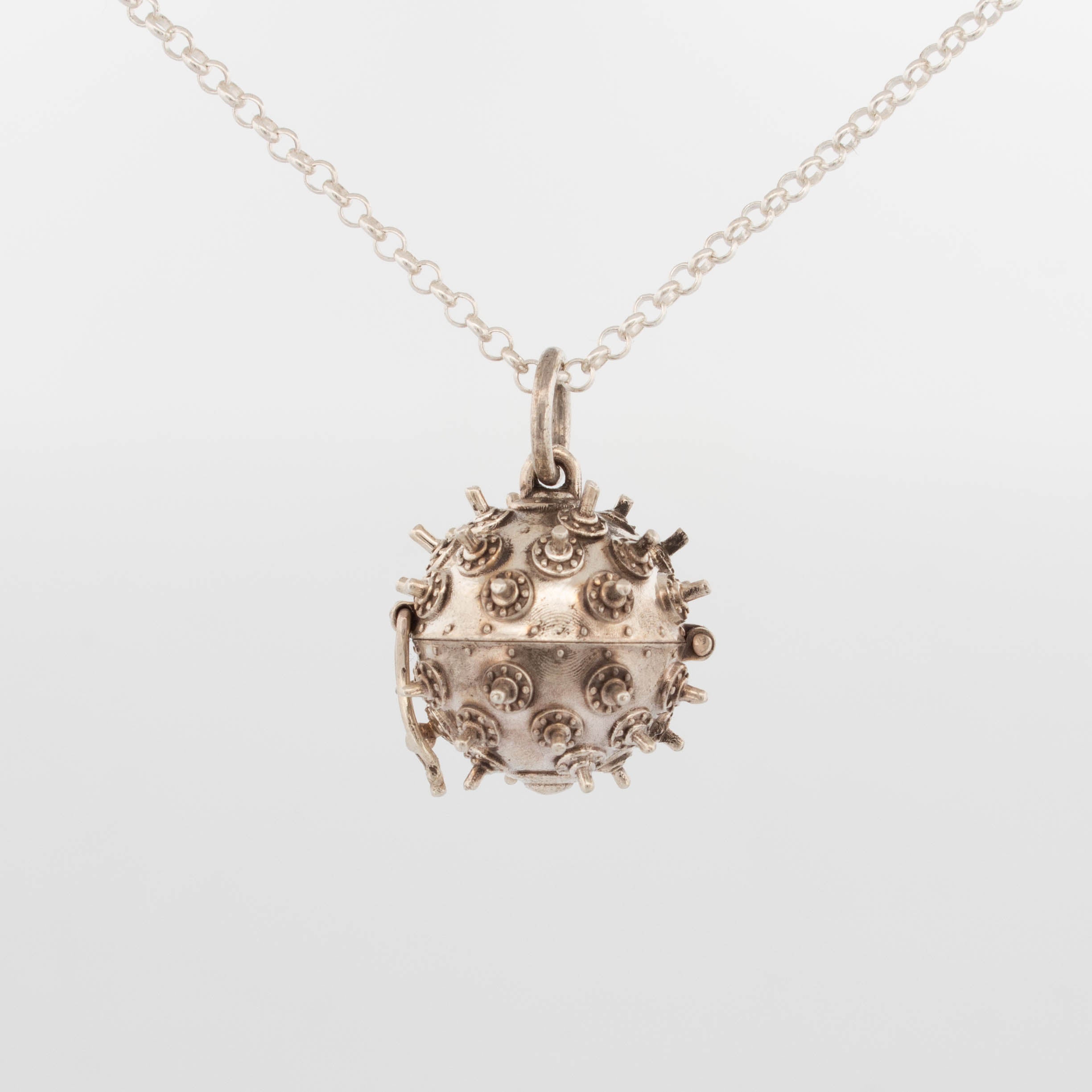 Small sterling silver deep sea mine pendant with raised rivet and spike detailing, functional hinge and clasp allowing it to open; suspended on a fine silver chain, handcrafted kinetic jewellery inspired by naval design.