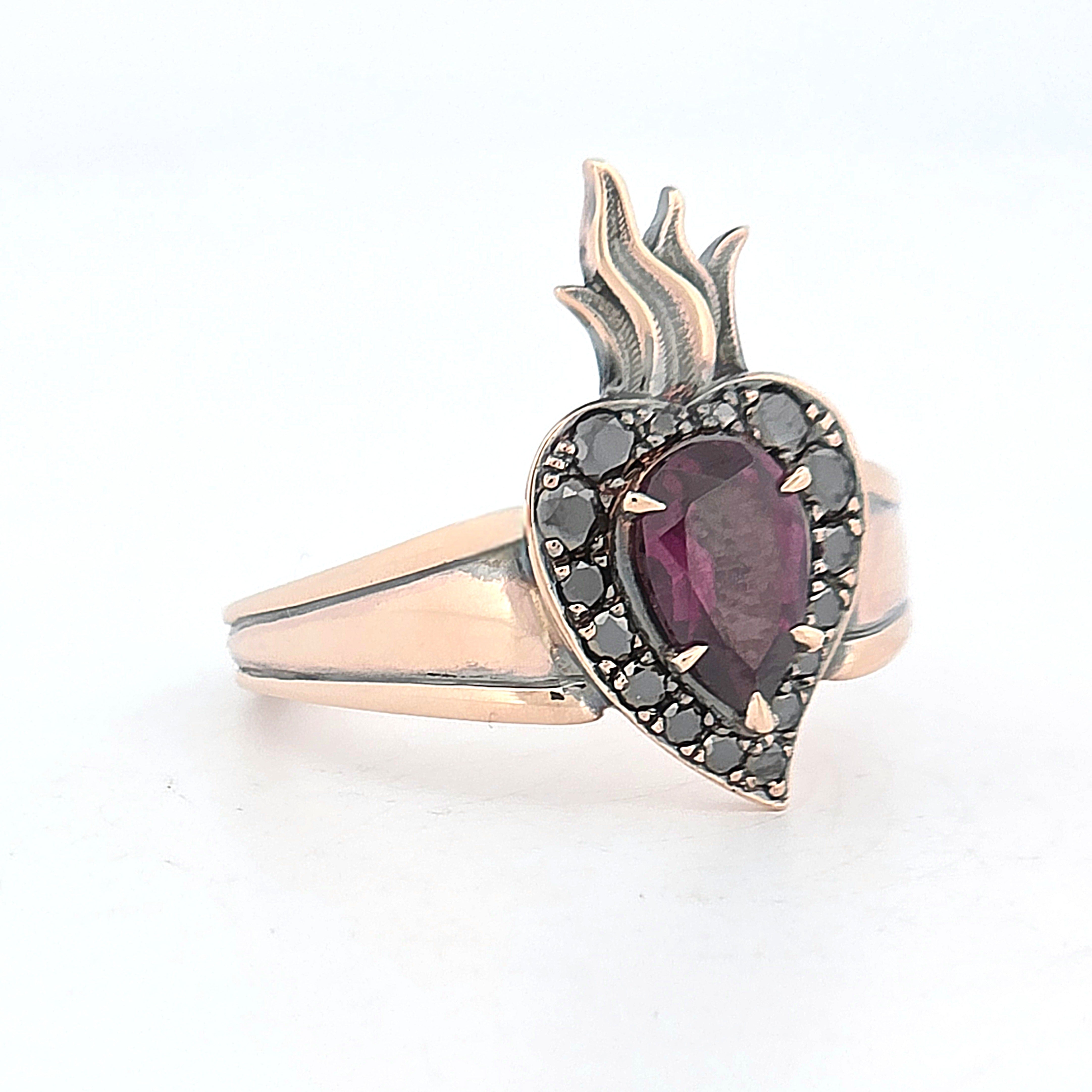 Rose gold flaming heart ring featuring a pear-shaped garnet surrounded by black diamonds.