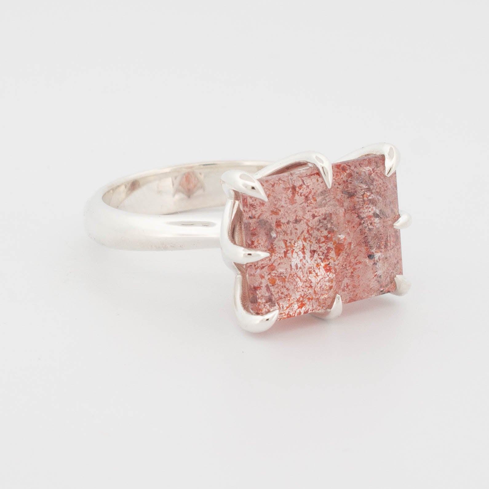 side view of "Sterling silver ring featuring a large rectangular cabochon with a red and copper-toned splatter effect, secured by bold claw prongs; contemporary statement design known as the Splatter Ring."