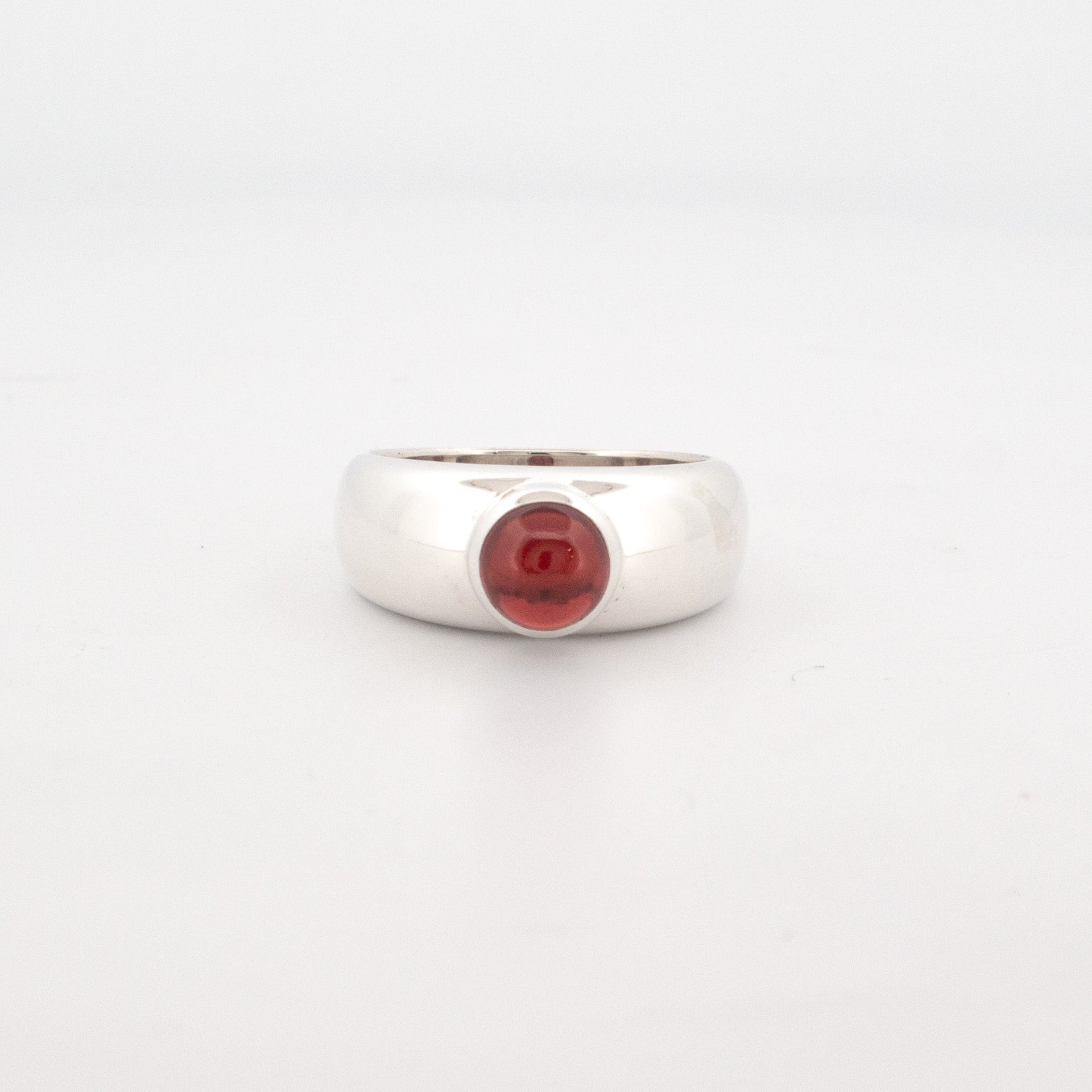 Sterling silver dome ring with a bezel-set 6mm round cabochon garnet gemstone.