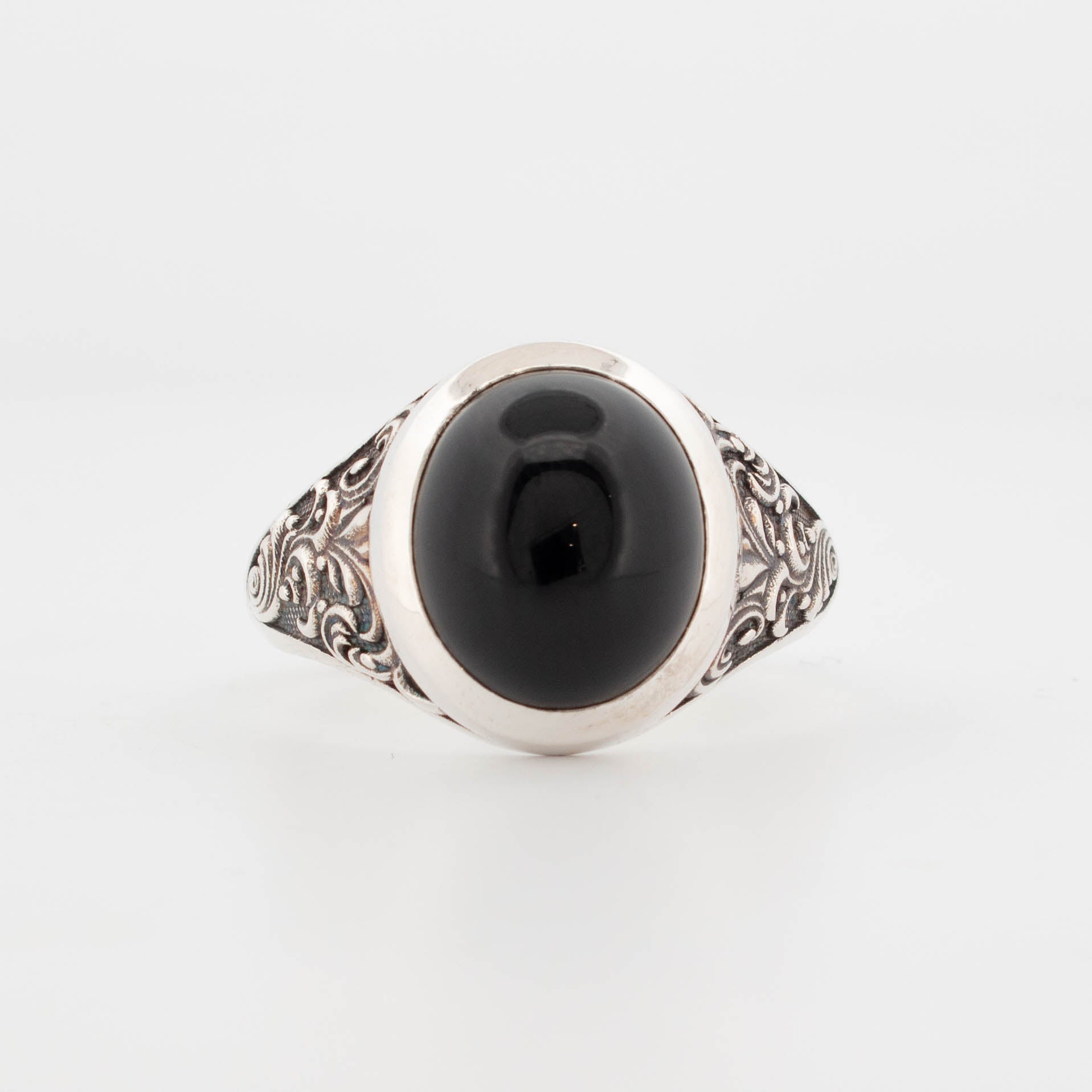 Large sterling silver ring featuring a bold oval cabochon black onyx set in a smooth bezel. The wide band is adorned with intricate, oxidised scrollwork and filigree detailing, giving the piece a vintage, gothic-inspired aesthetic. A dramatic statement ring perfect for lovers of dark gemstones, bold silver jewellery, and artisanal handcrafted designs.