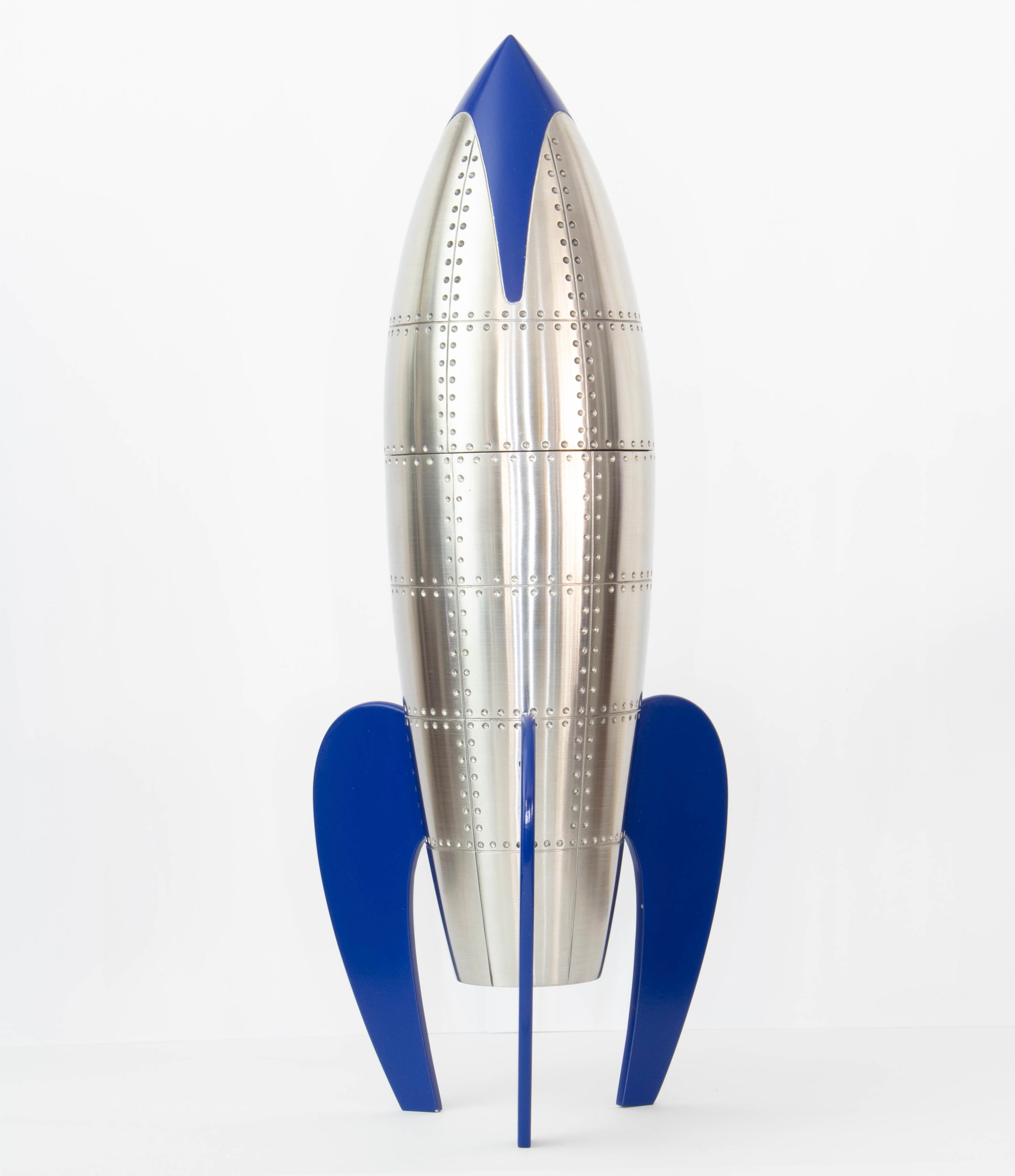 Custom cremation urn designed in the form of a retro rocket, crafted from stainless steel and brass with rivet detailing, and finished with glossy blue enamel fins and nose cone; stands 34cm tall.