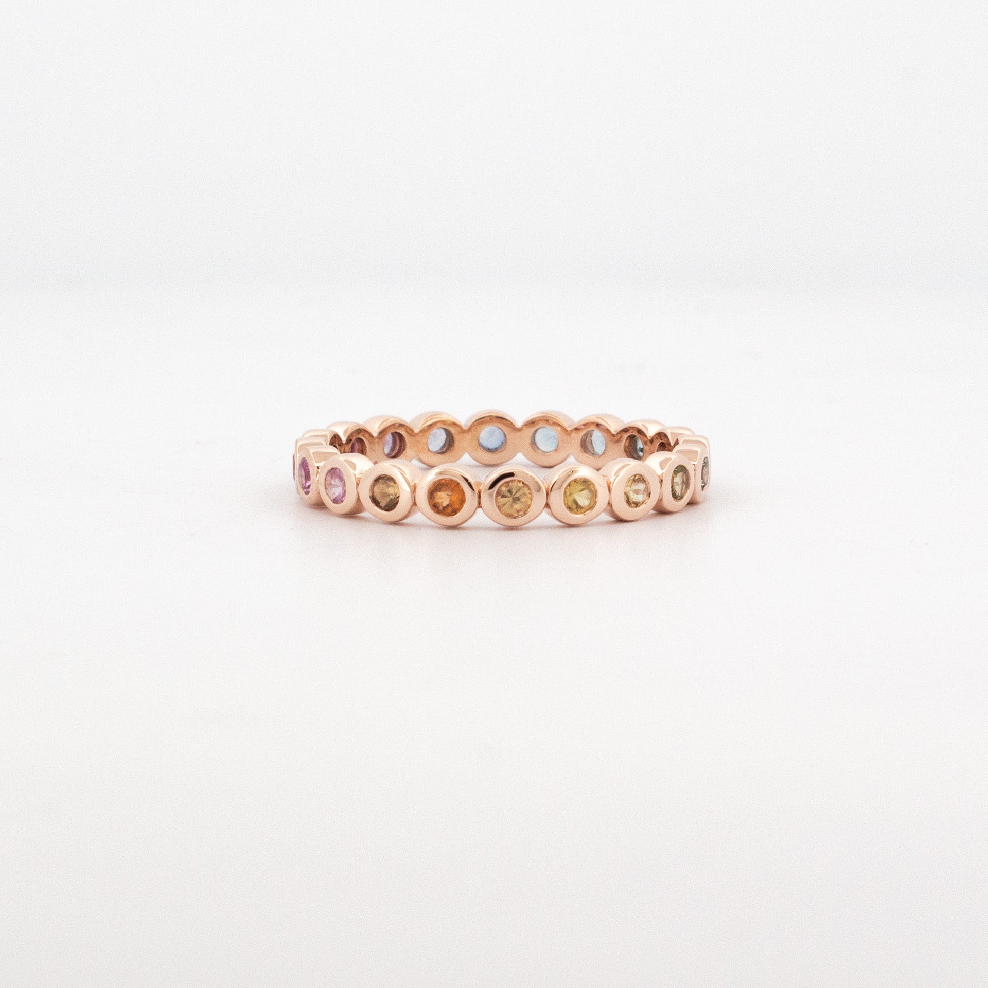 9ct rose gold full eternity ring bezel set with pastel colourfade sapphires in round settings and open gallery detailing.