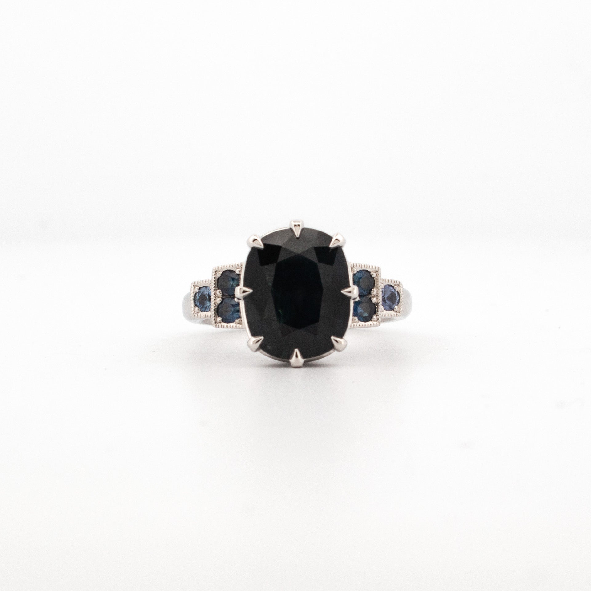 A platinum ring featuring a large central Australian Sapphire with smaller coloured gemstone accents on the shoulders.