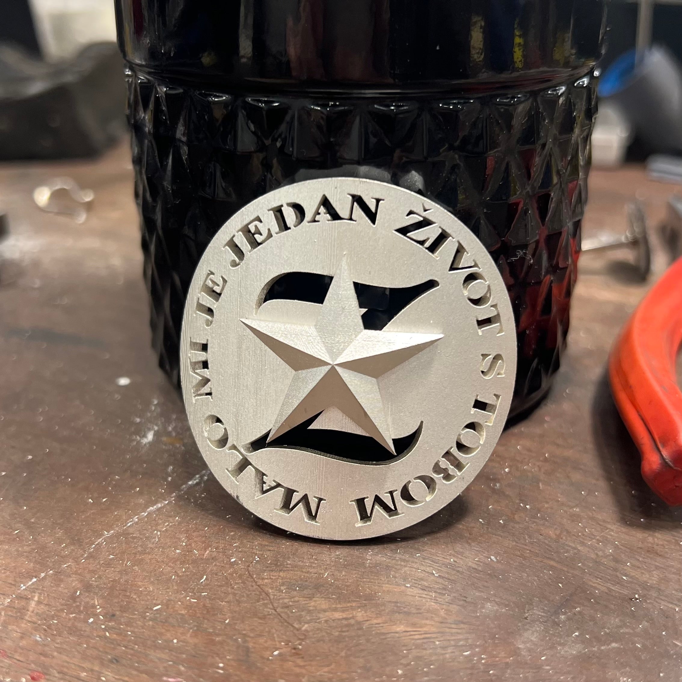 Custom memorial urn crafted in the form of a textured wine bottle, made in sterling silver with engraved Croatian lyrics 'Malo mi je jedan život s tobom' and a central star emblem; designed to hold ashes and honour a beloved husband, father, grandfather, and friend with a love of red wine, family, and music.