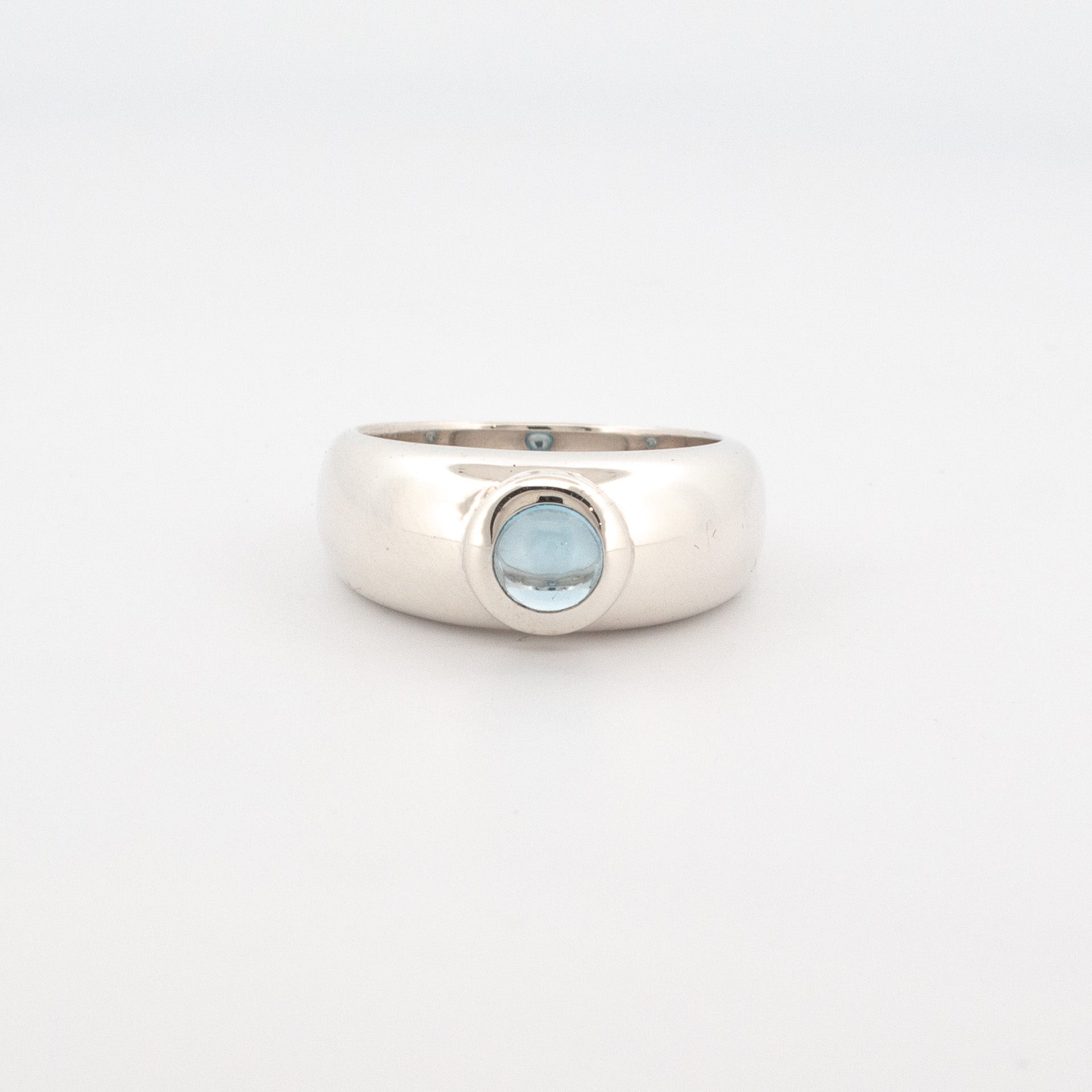 Sterling silver dome ring with a 5mm round cabochon-cut blue topaz bezel-set at the centre.