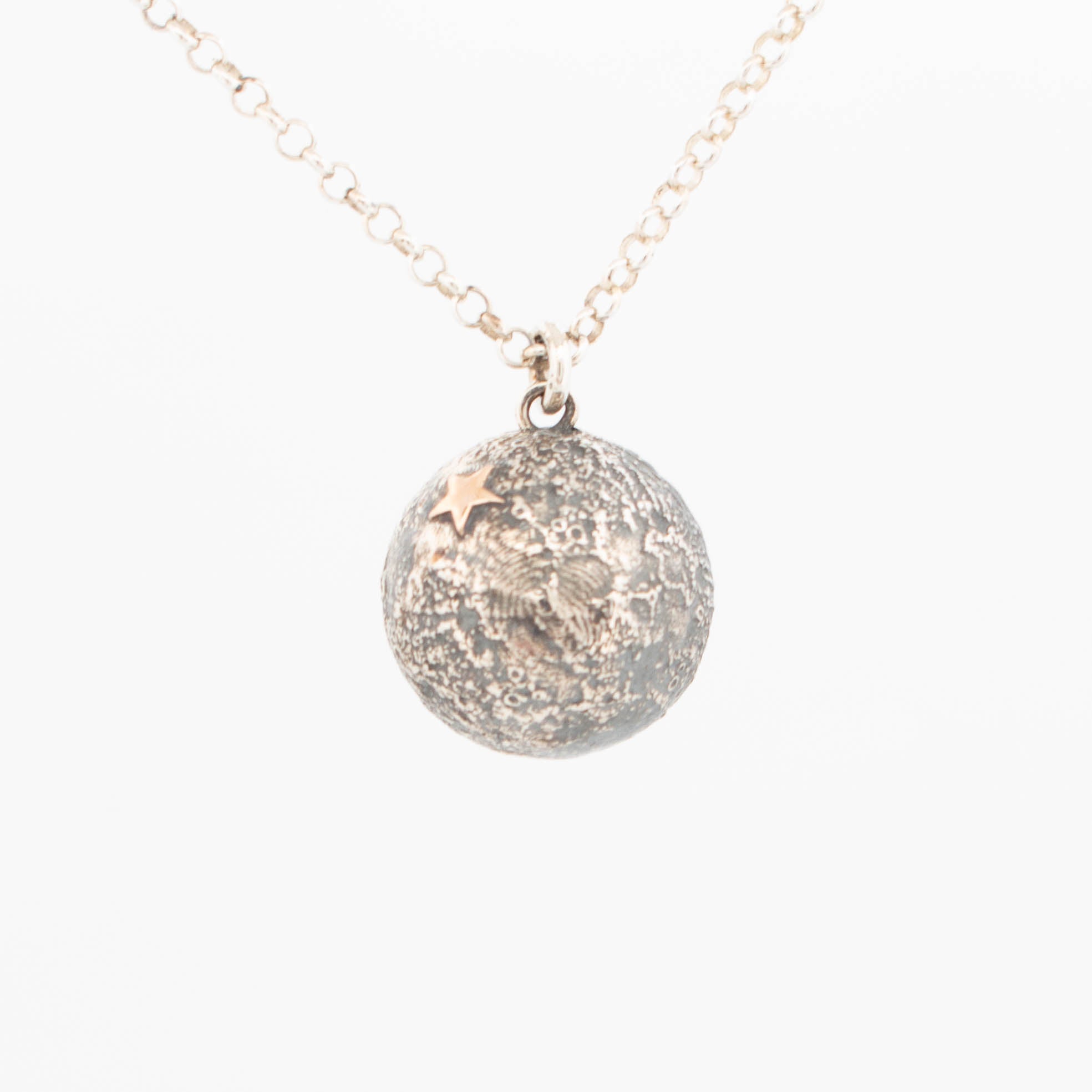 15mm Small sterling silver moon pendant with textured topographical surface resembling lunar craters, accented with a tiny 9ct rose gold star; suspended on a fine silver chain, handcrafted celestial-themed jewellery.