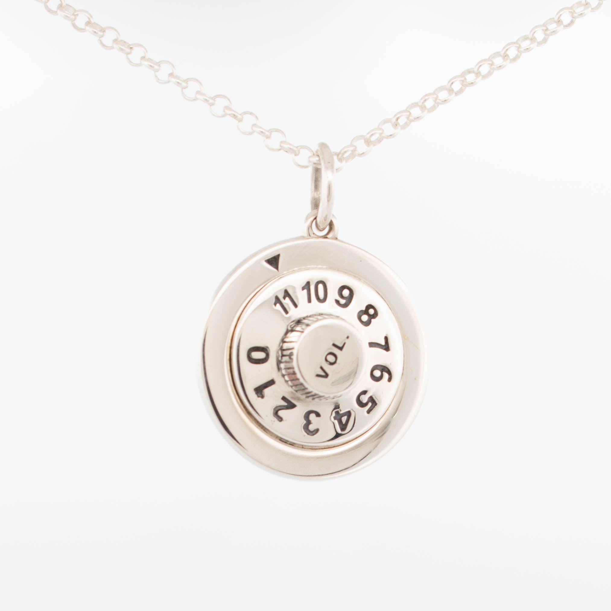 Sterling silver volume knob pendant engraved with numbers 0–11 and “VOL.” text, designed to resemble a classic guitar amp dial, suspended on a fine silver chain; handcrafted music-themed jewellery for rock and roll lovers.