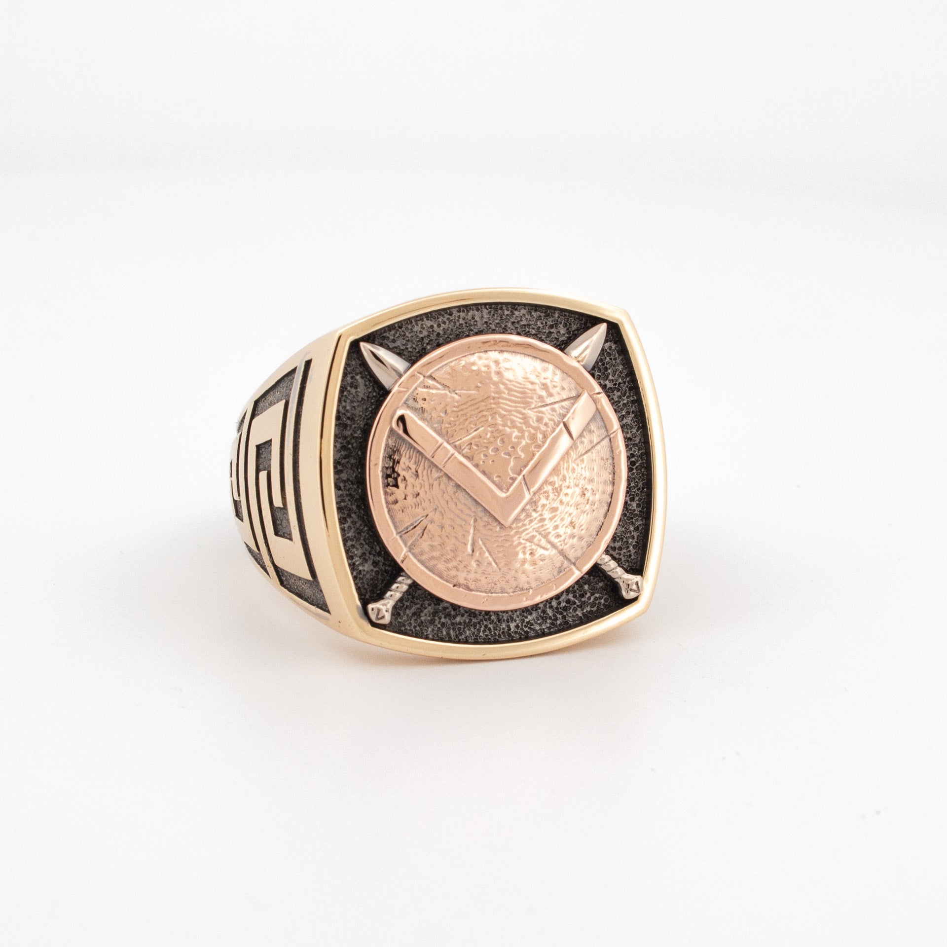 18ct recycled gold Spartan shield signet ring with yellow, rose, and white gold alloy, black rhodium detail, and Greek Key pattern on the shank.