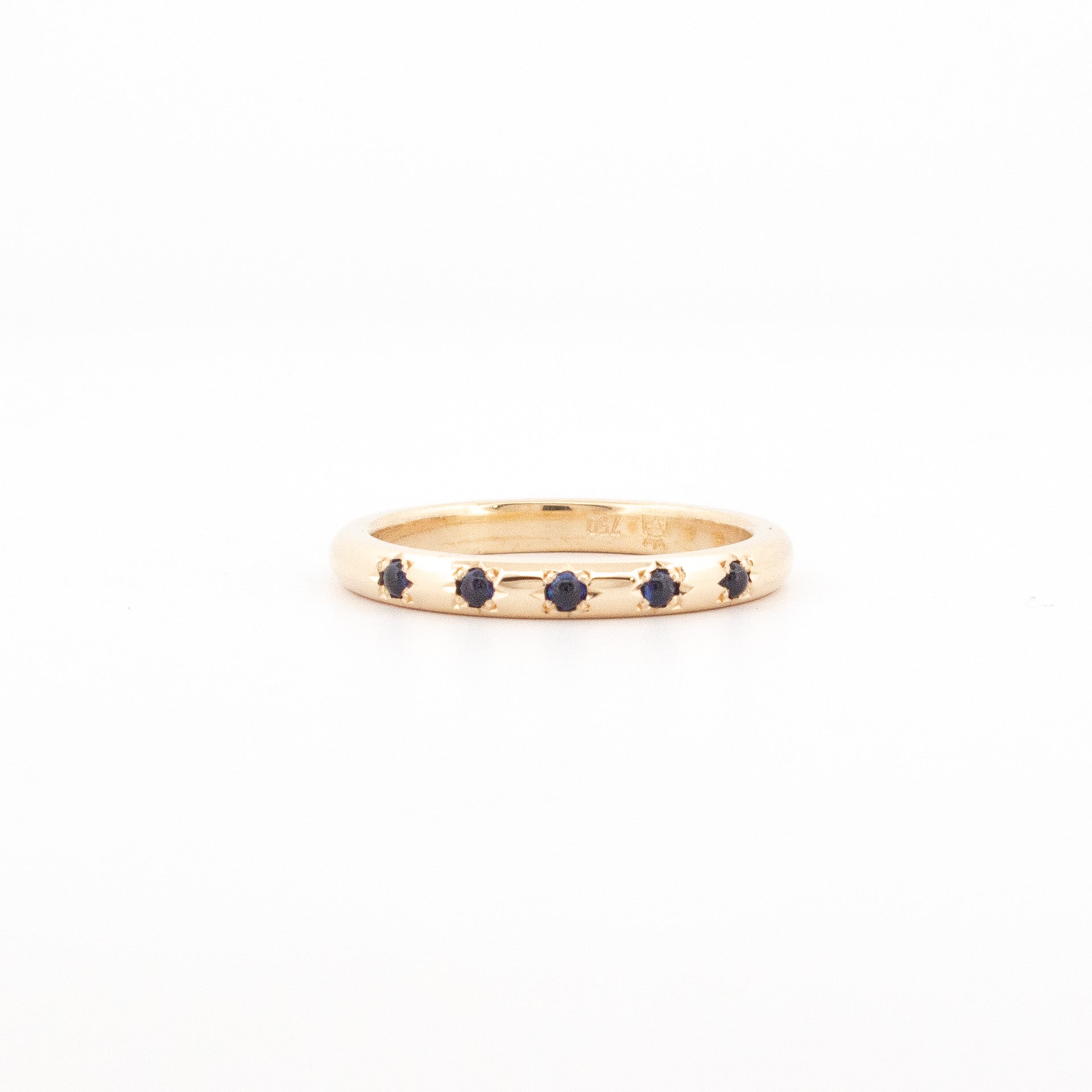 18ct yellow gold ring with five round blue sapphires star-set across the polished band.