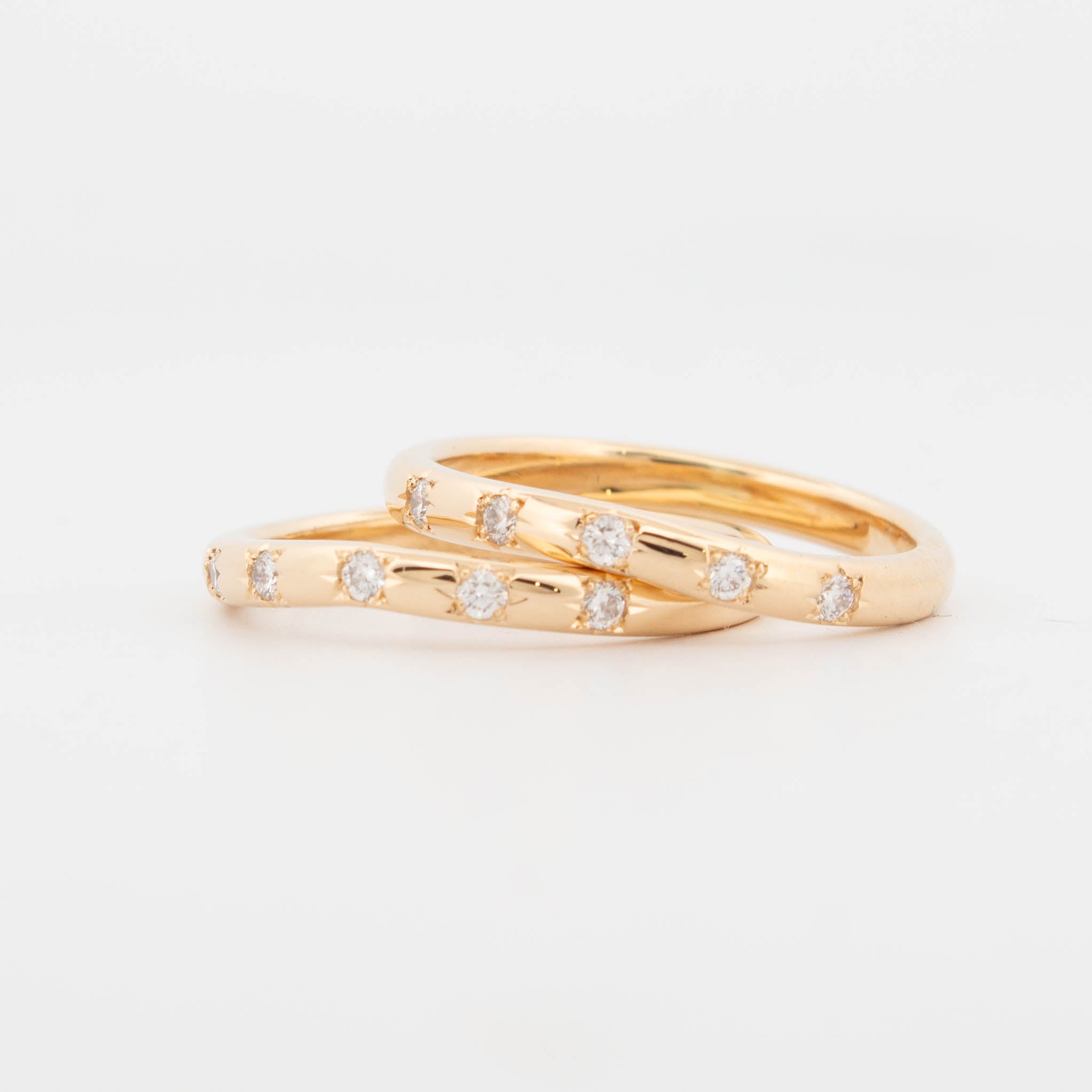 Pair of 18ct yellow gold wedding rings featuring round brilliant-cut diamonds in star settings, evenly spaced across gently curved polished bands