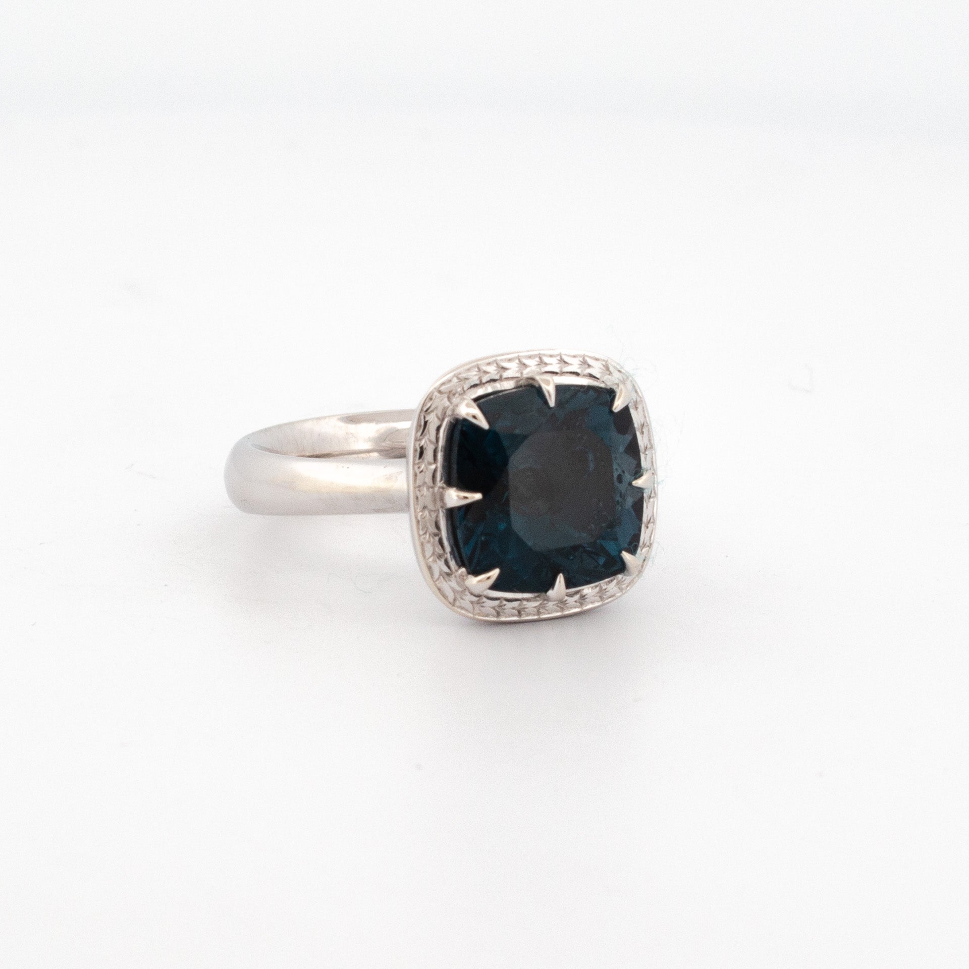 9ct white gold ring with 11mm cushion cut London Blue Topaz and hand-engraved halo detailing.
