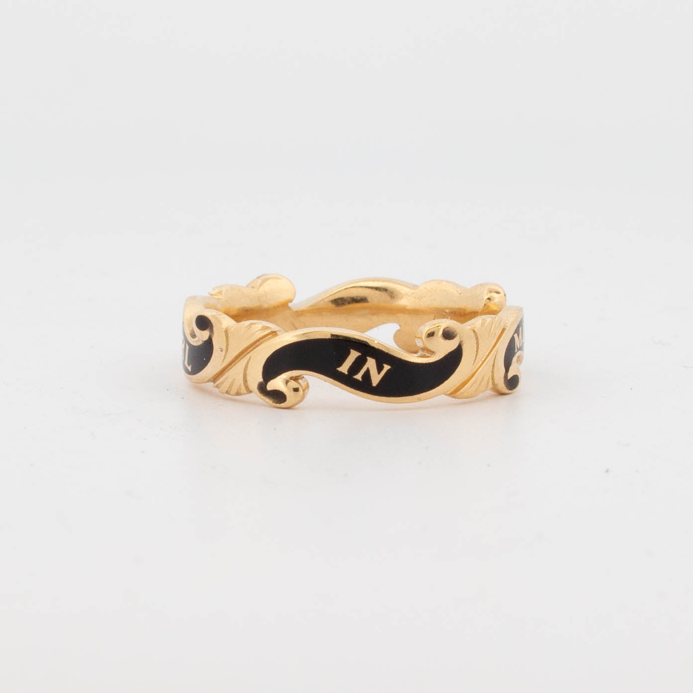 18ct yellow gold memorial ring with black enamel scrollwork, engraved with the inscription 'IN MEMORY OF CARL' around the band; designed as a tribute piece with ornate ribbon-like detailing.