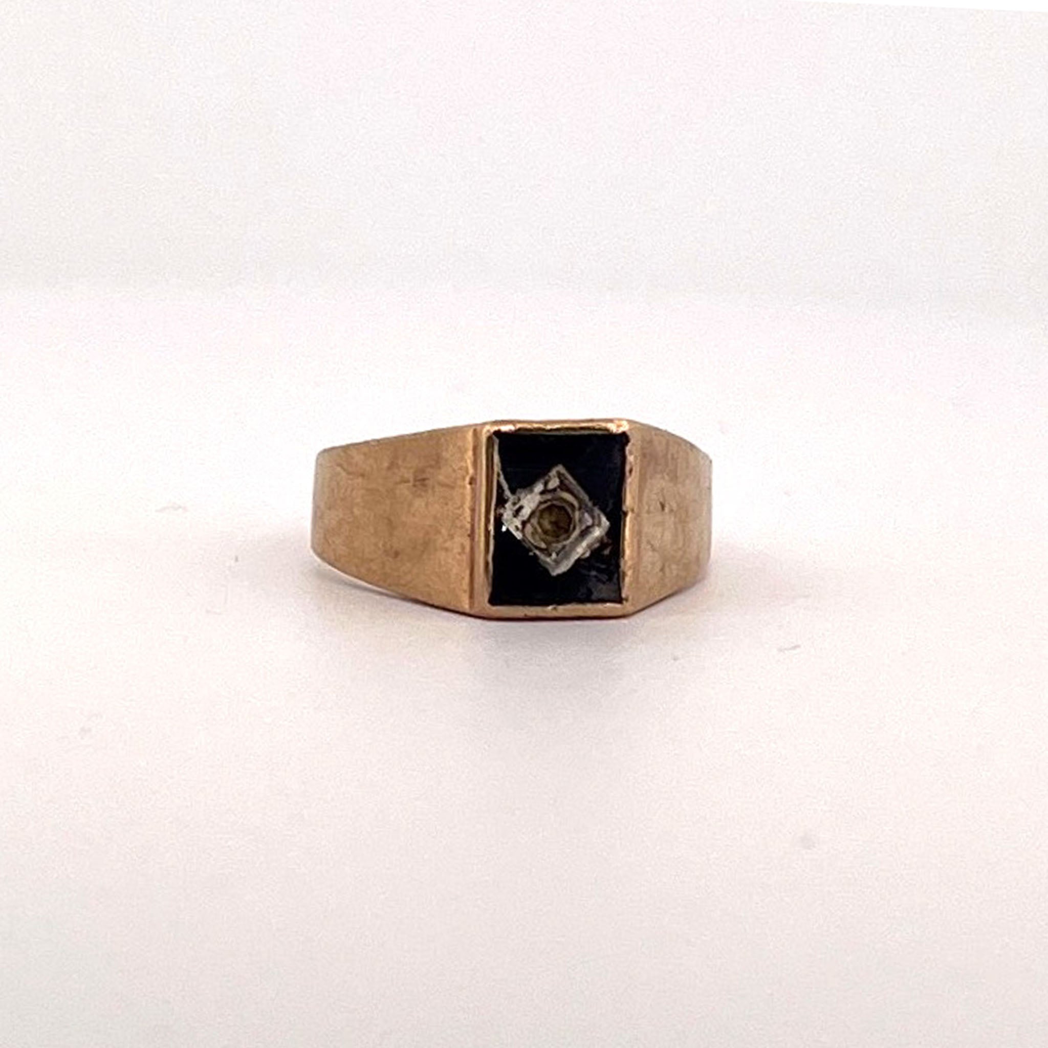 Yellow gold ring with rectangular black onyx centre, bezel-set round diamond in square setting, and diamond-accented shoulders.