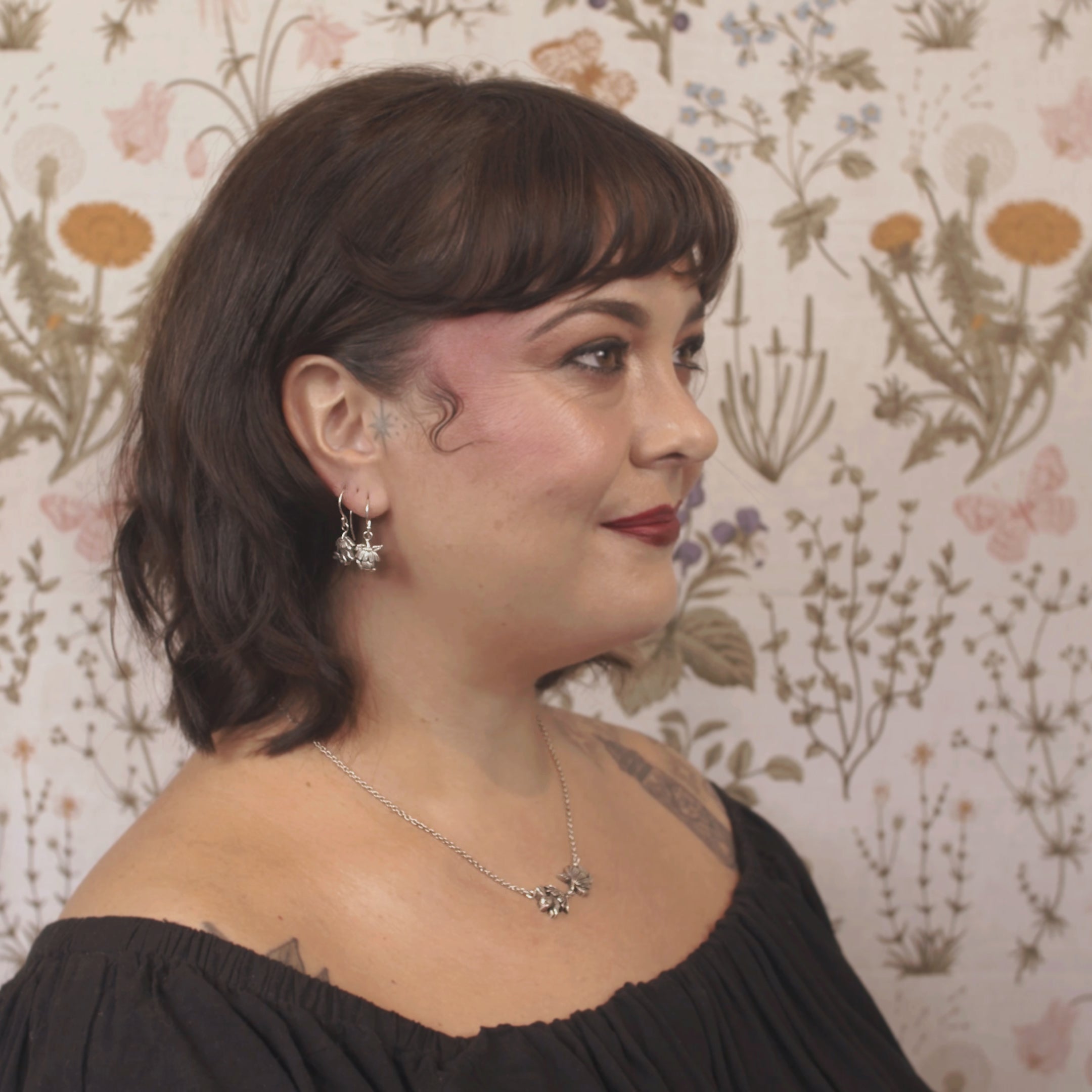 Sterling silver drop earrings with sculpted half bunny forms under layered daisy flower caps, handmade woodland jewellery