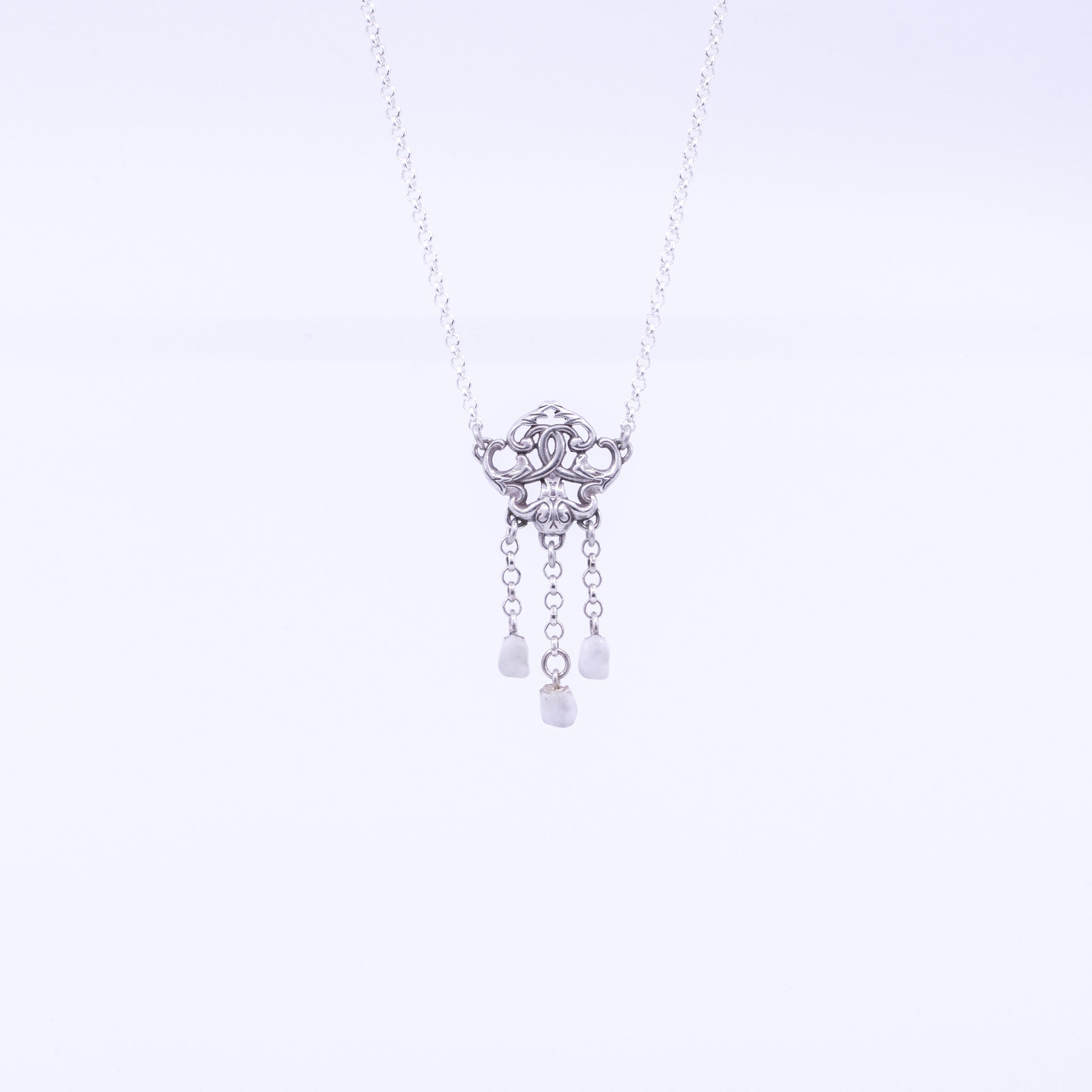 Sterling silver necklace featuring antique-style key pendant with ornate scrollwork, suspended chains holding three polished children’s teeth as unique pendant drops.