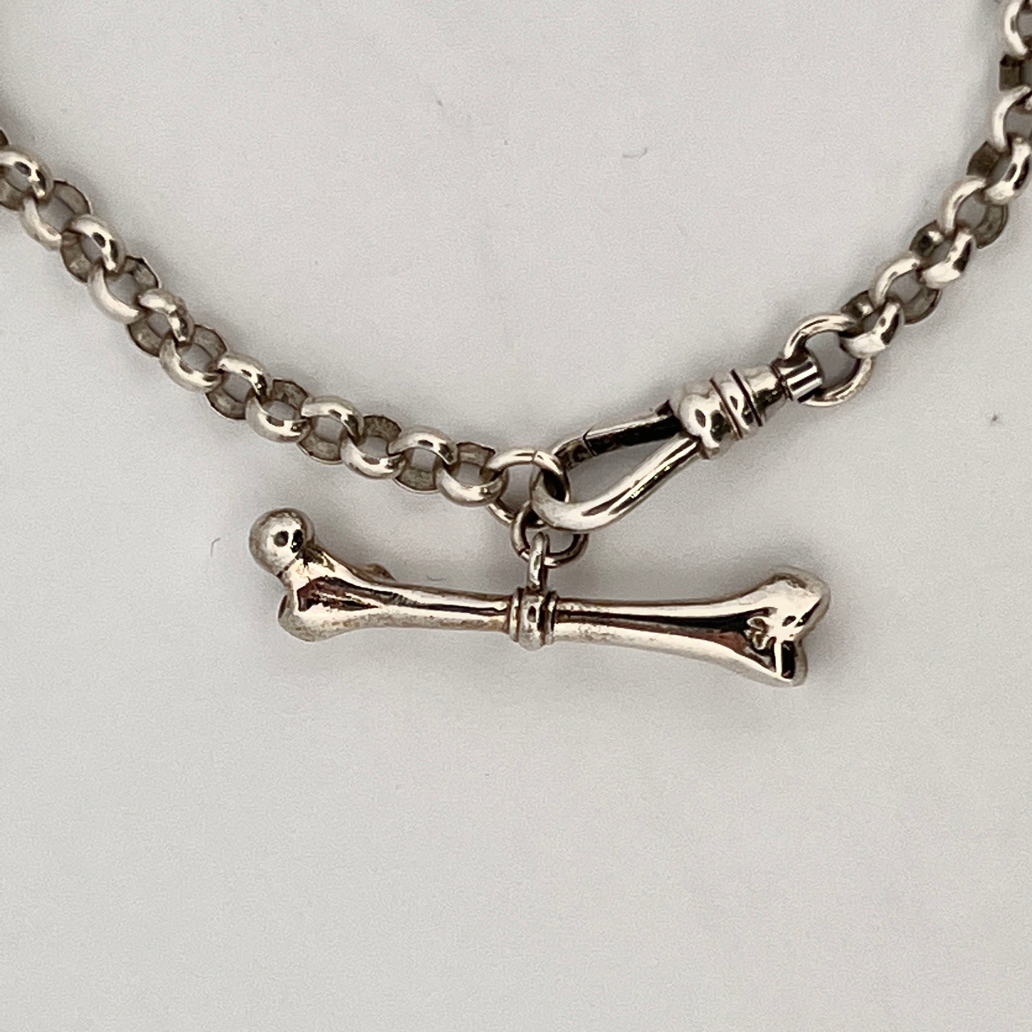 Sterling silver bone charm with anatomical shape and polished finish, suitable for charm bracelet or pendant necklace.