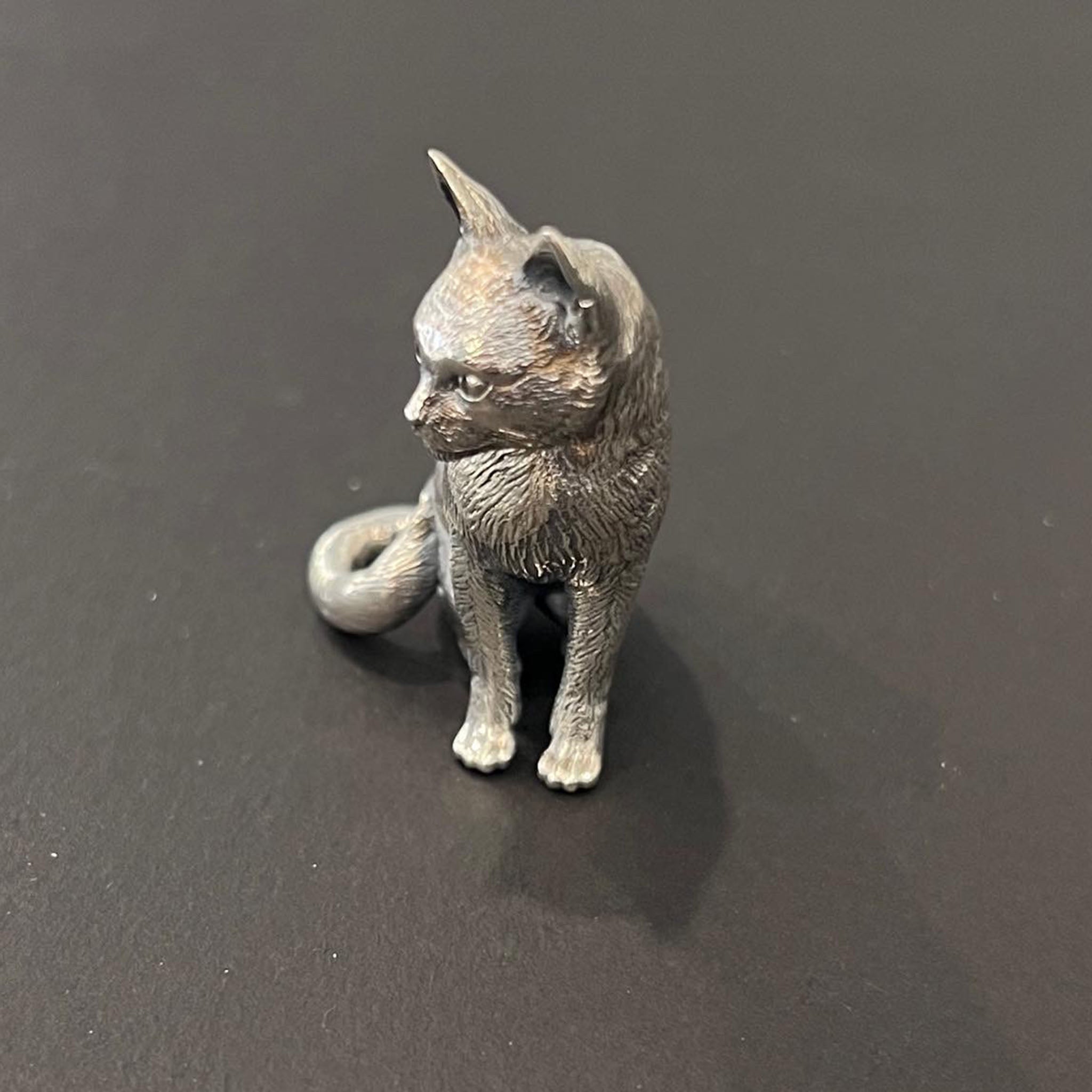 A sterling silver cat memorial sculpture with a textured surface and a curved tail, designed as a one-off commission piece.