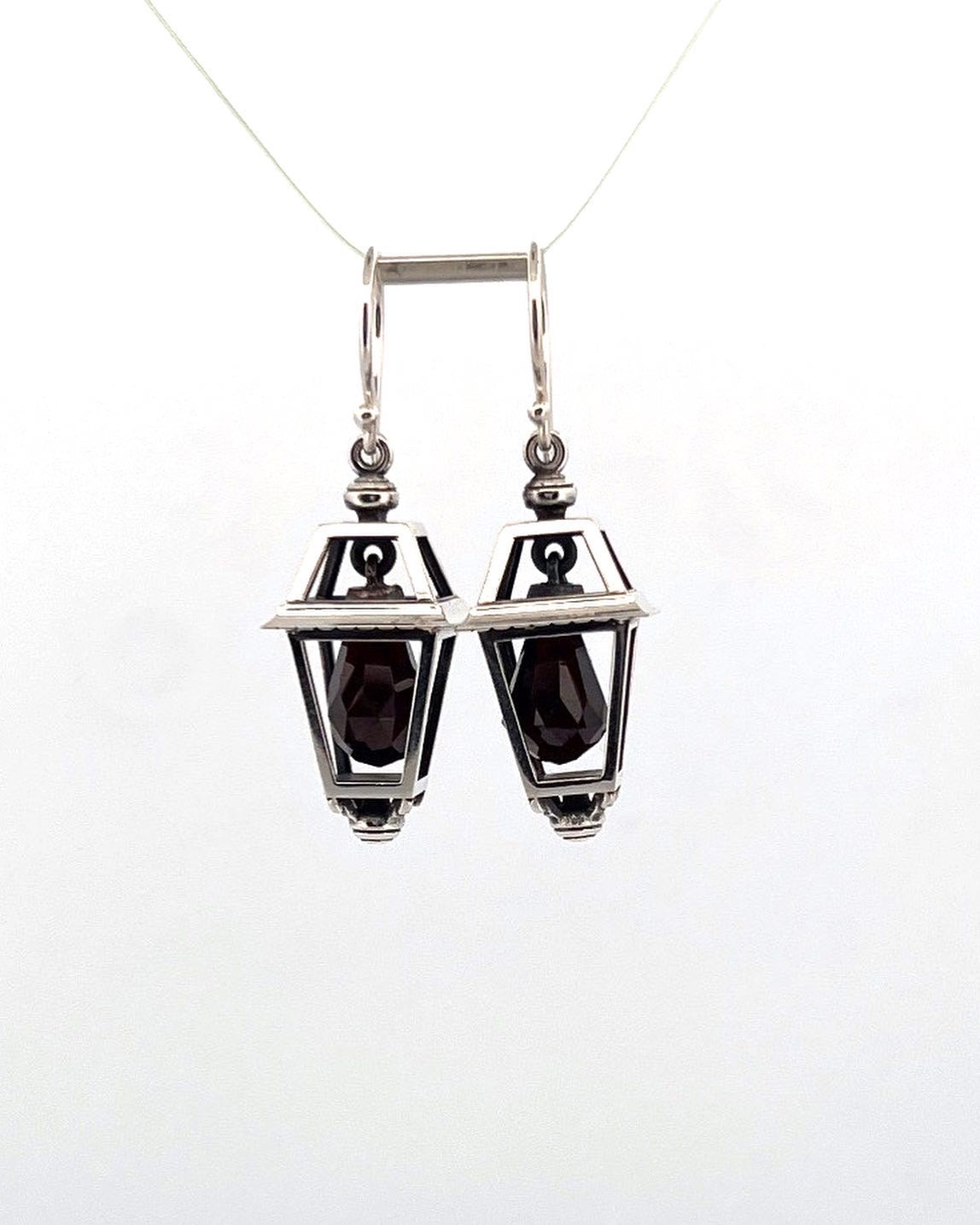 A pair of sterling silver earrings designed after Victorian streetlamps, featuring garnet briolettes.