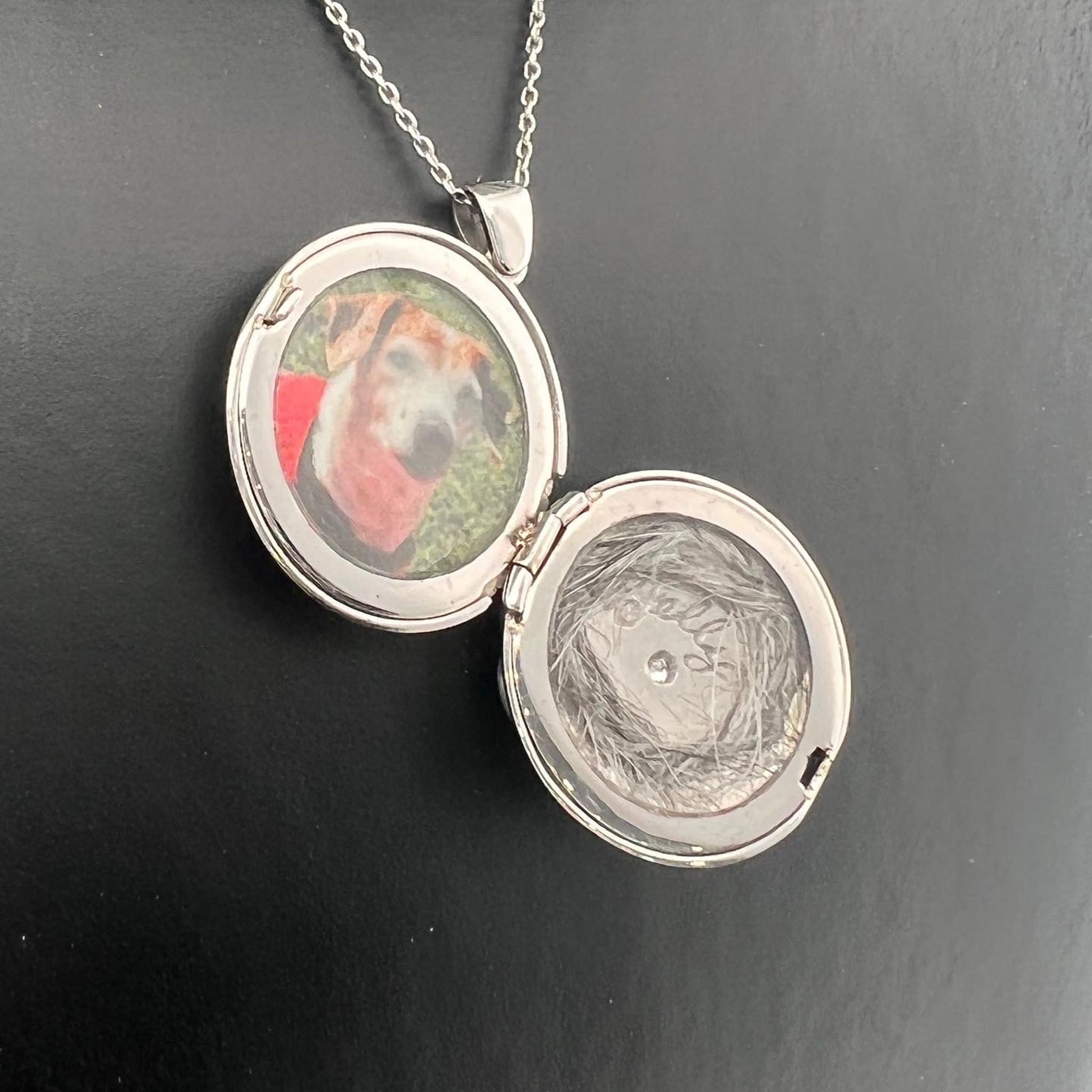 18ct white gold memorial locket pendant with engraved scrollwork border, central starburst engraving set with round brilliant cut diamond, suspended on fine chain.