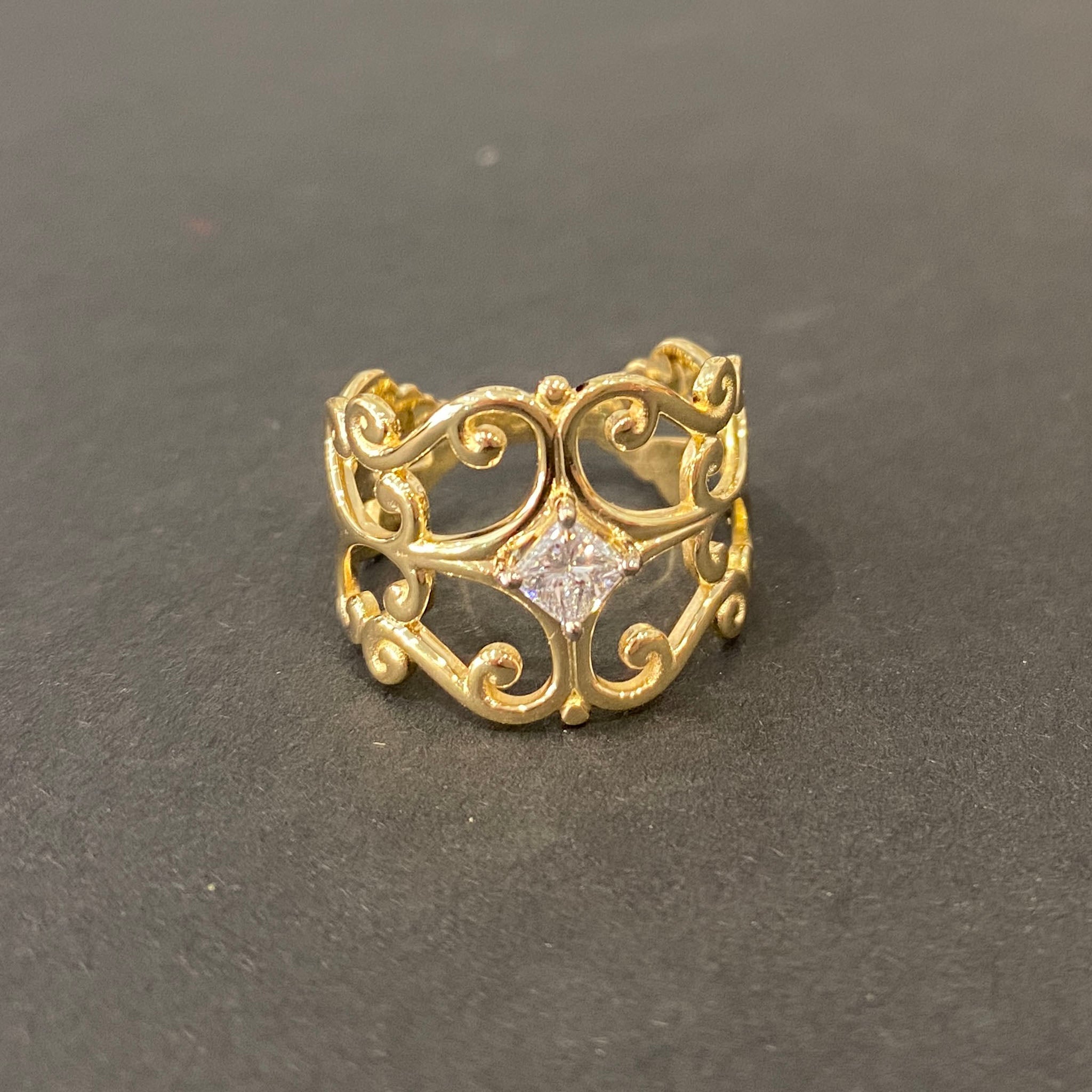 Yellow gold scrollwork ring featuring a central princess-cut diamond in claw setting, crafted by reusing gold and diamond from an old ring.