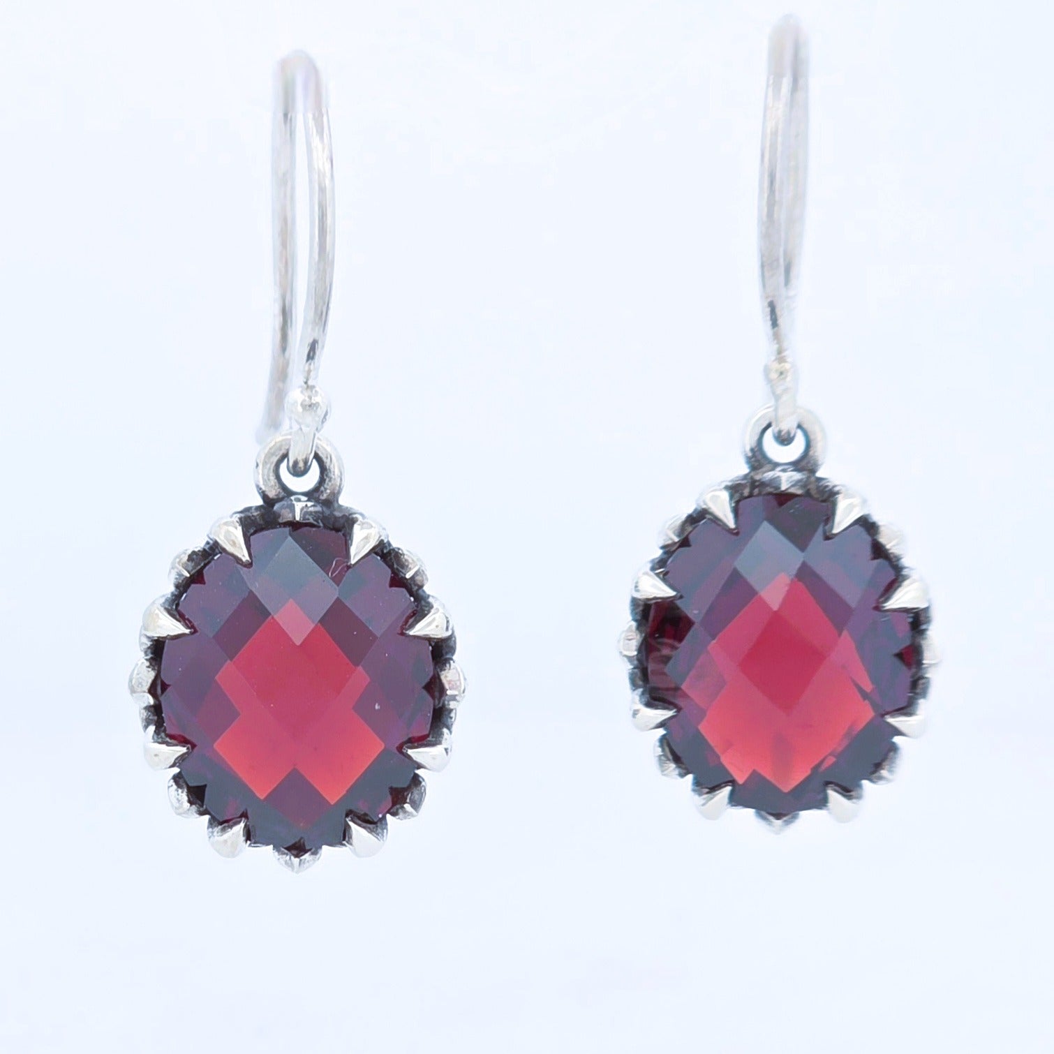 Sterling silver hand made claw set earrings with faceted oval shaped  garnets