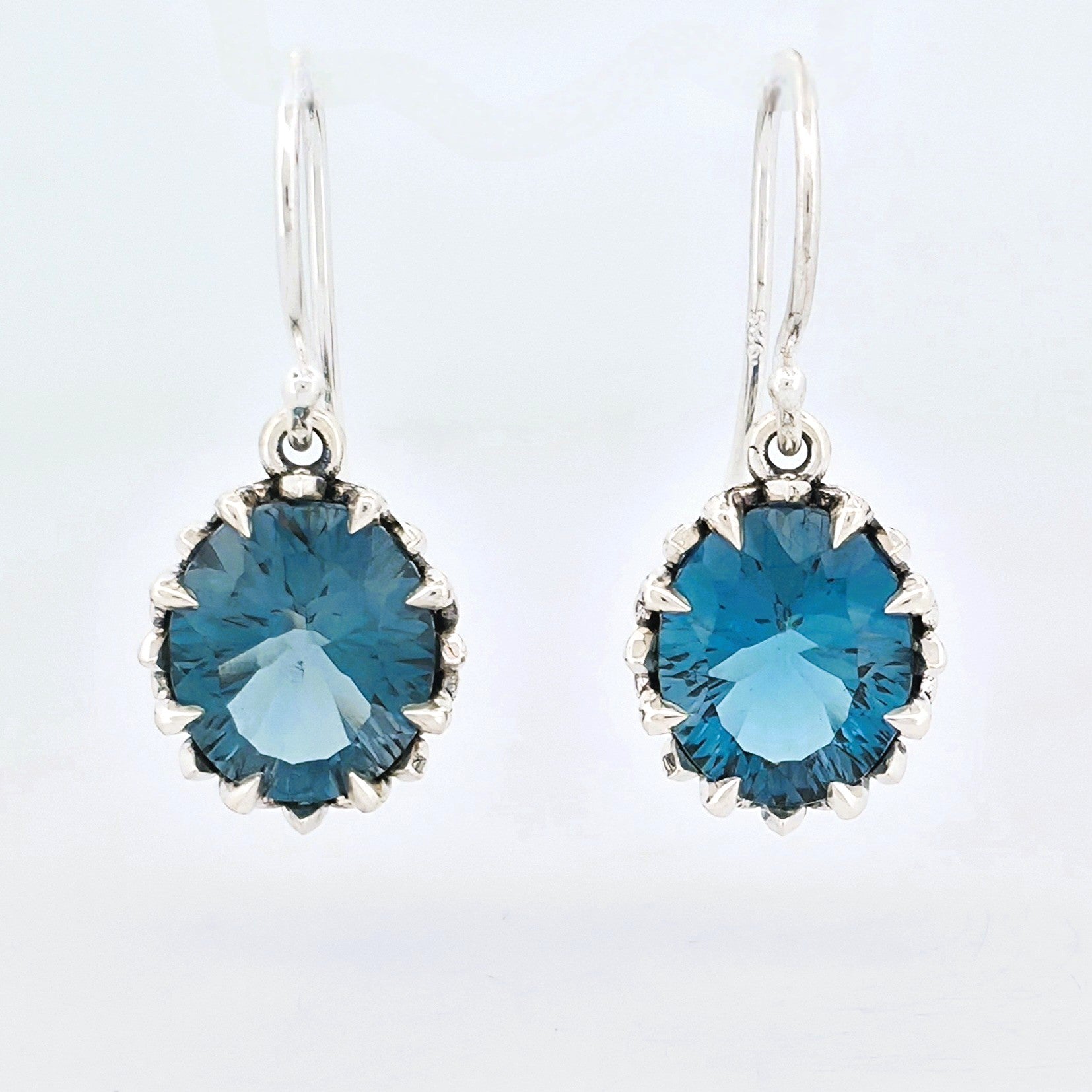 Sterling silver hand made claw set earrings with faceted oval shaped  london blue topaz