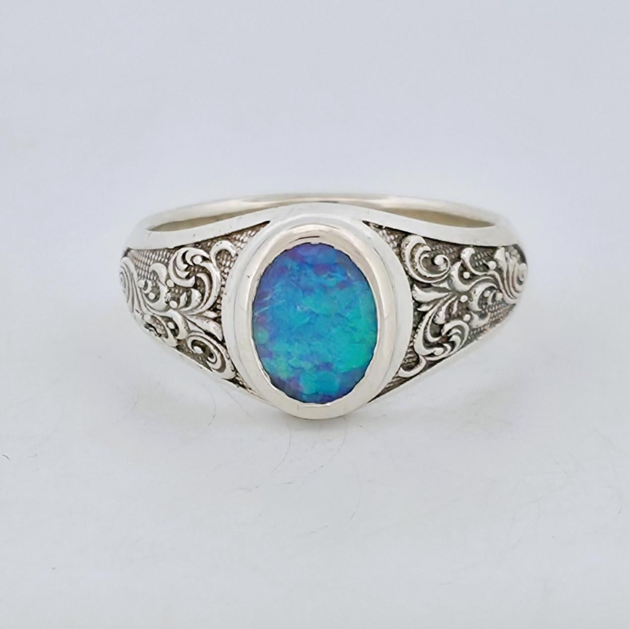 A sterling silver ring featuring an oval Opal with engraved shoulder details.