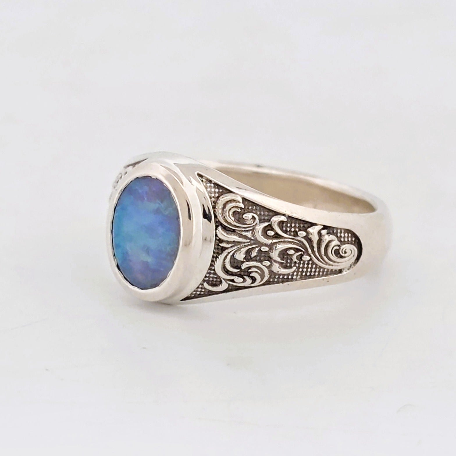 A sterling silver ring featuring an oval Opal with engraved shoulder details.