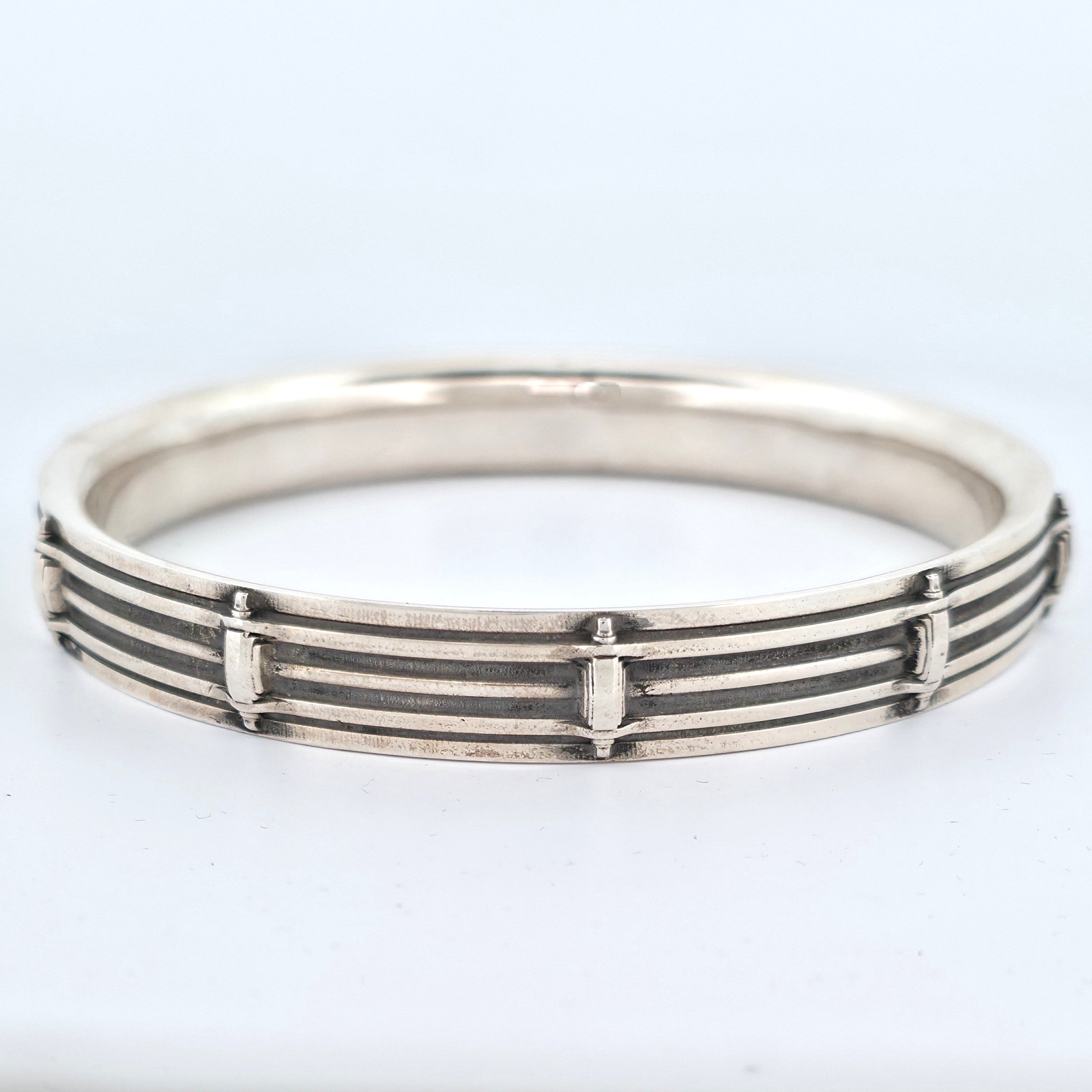 Sterling silver snare drum-inspired bangle with layered horizontal bands and raised vertical detailing