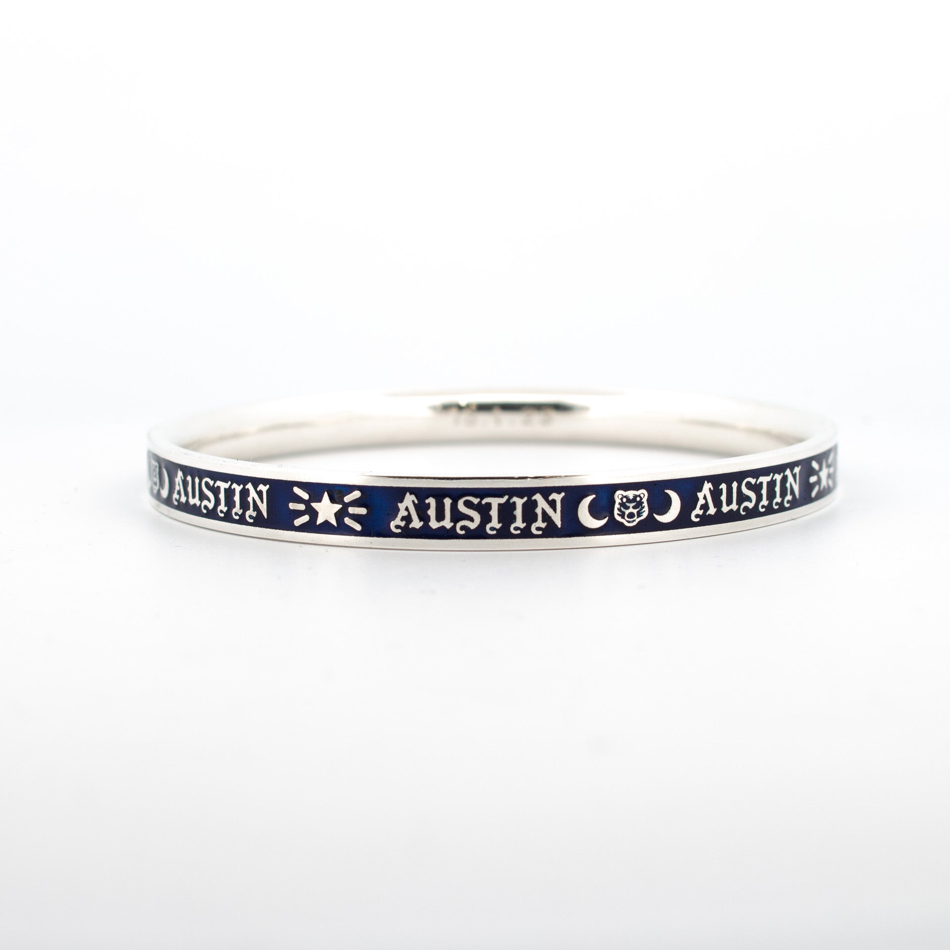 Sterling silver baby name bangle with dark blue enamel inlay, custom name engraving and symbolic icons.