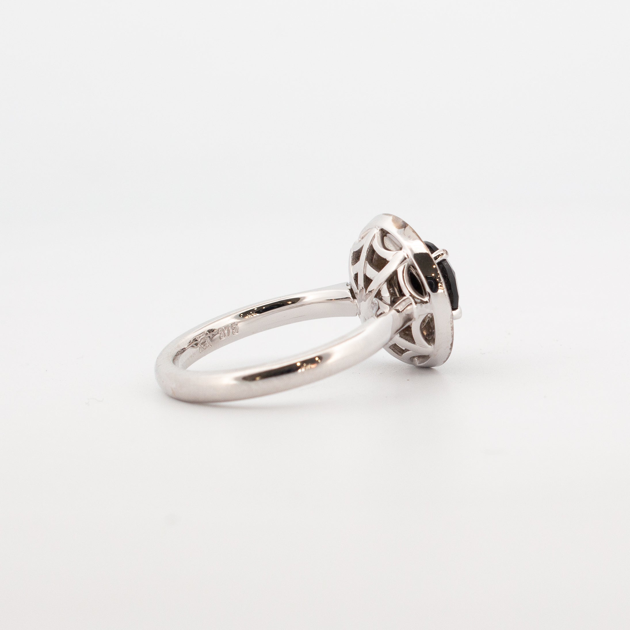 back view of the 9ct white gold double halo engagement ring featuring a round faceted black spinel centre stone, encircled by pavé-set white and black diamonds with hidden spiderweb detailing beneath the setting.