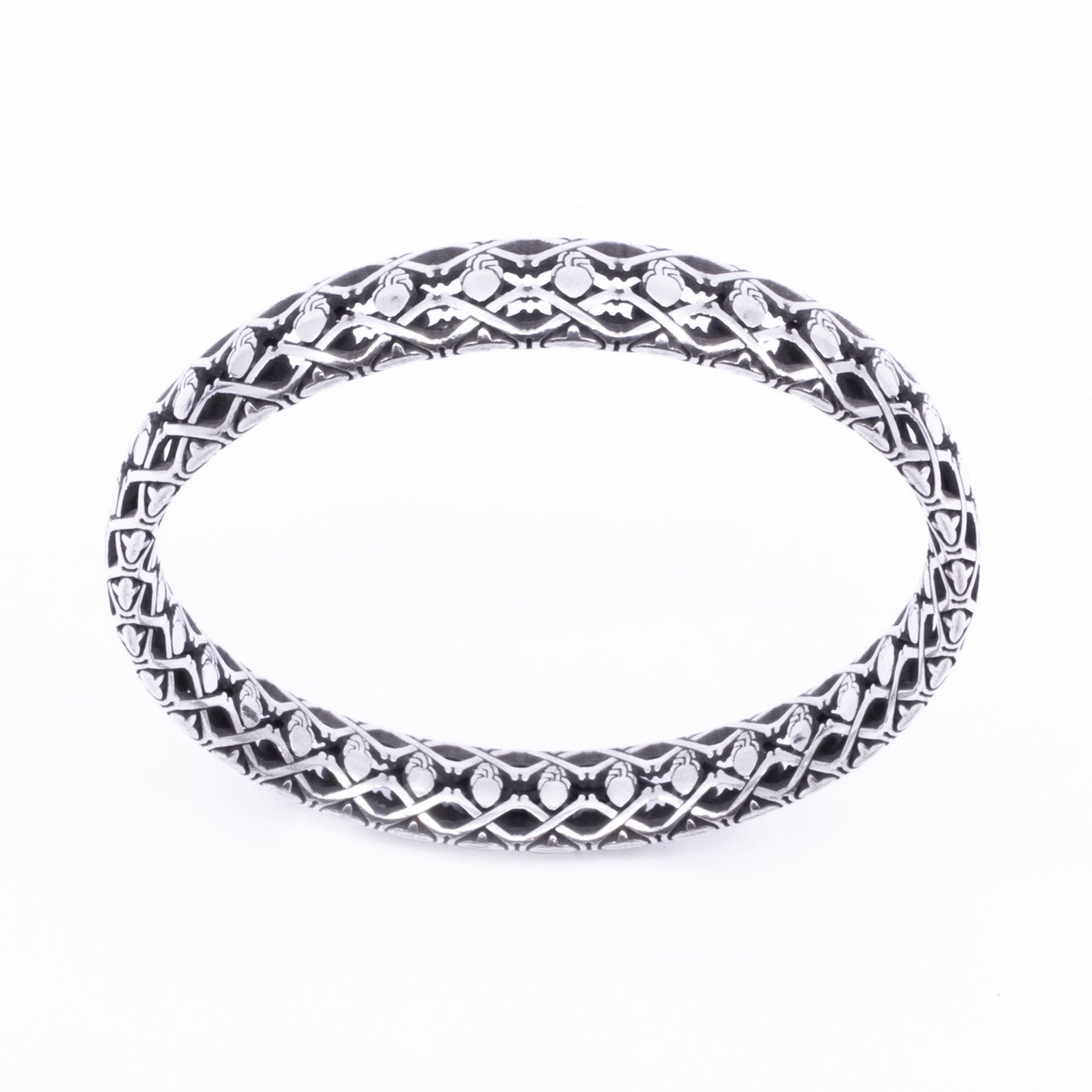 Oxidised sterling silver bangle with repeating anatomical heart and crossbones pattern in high-relief lattice design.