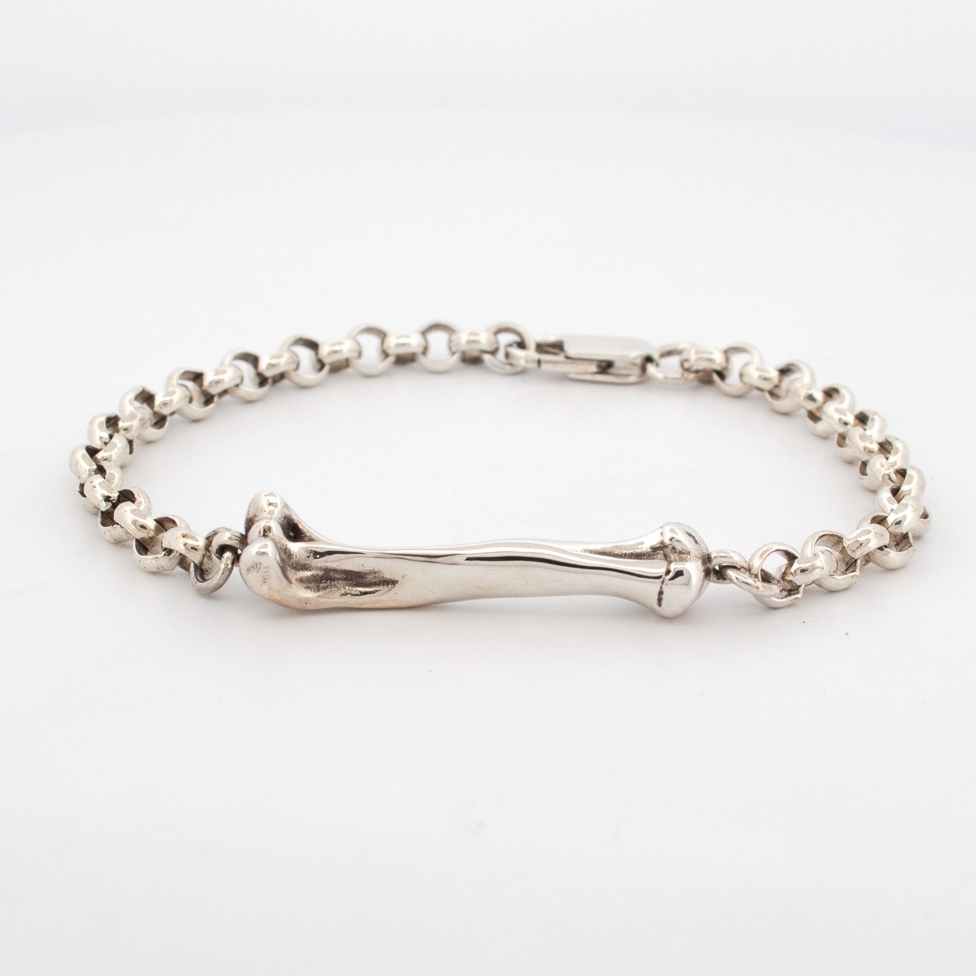 Sterling silver bracelet featuring a sculpted bone link centerpiece with round belcher chain and a hook clasp.