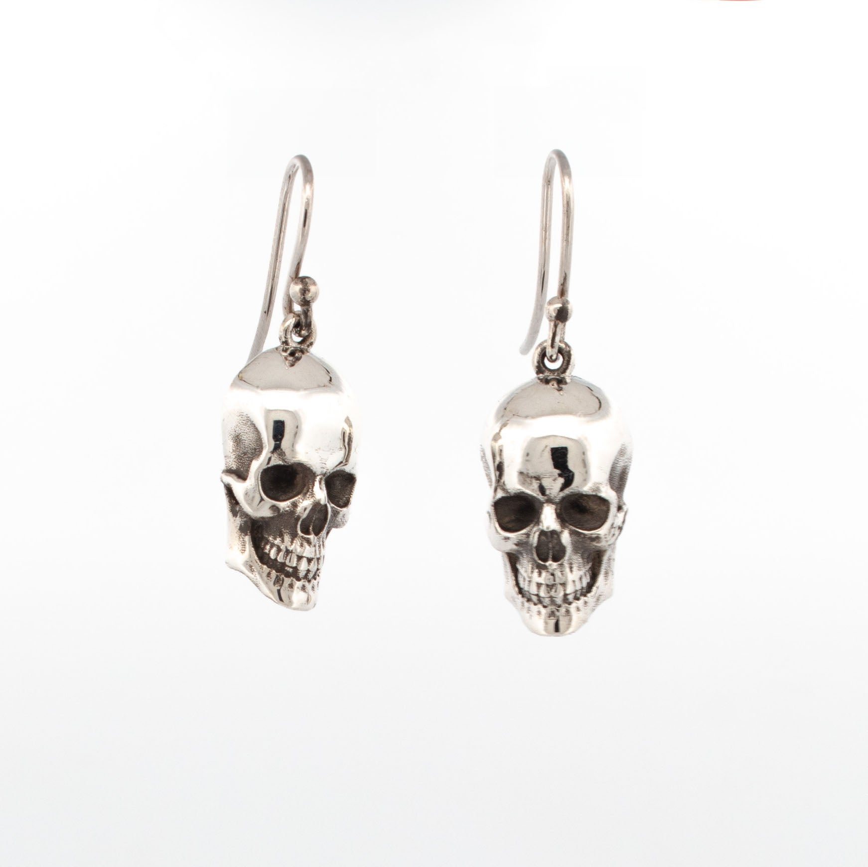 Sterling silver skull drop earrings with polished finish and oxidised eye sockets.