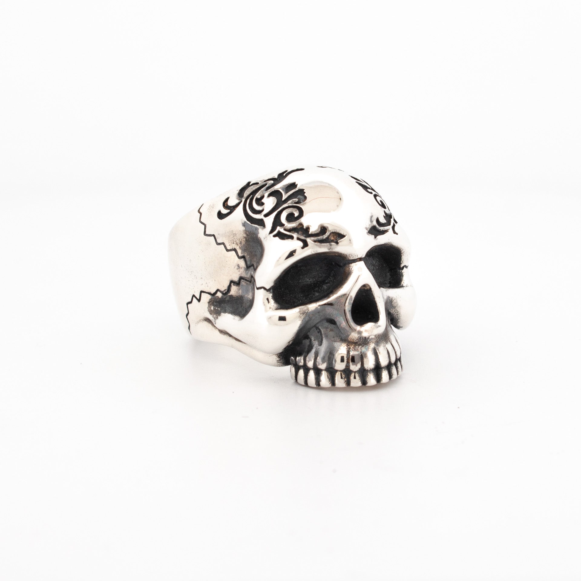 Sterling silver skull ring with black enamel scroll engraving and oxidised eye sockets.