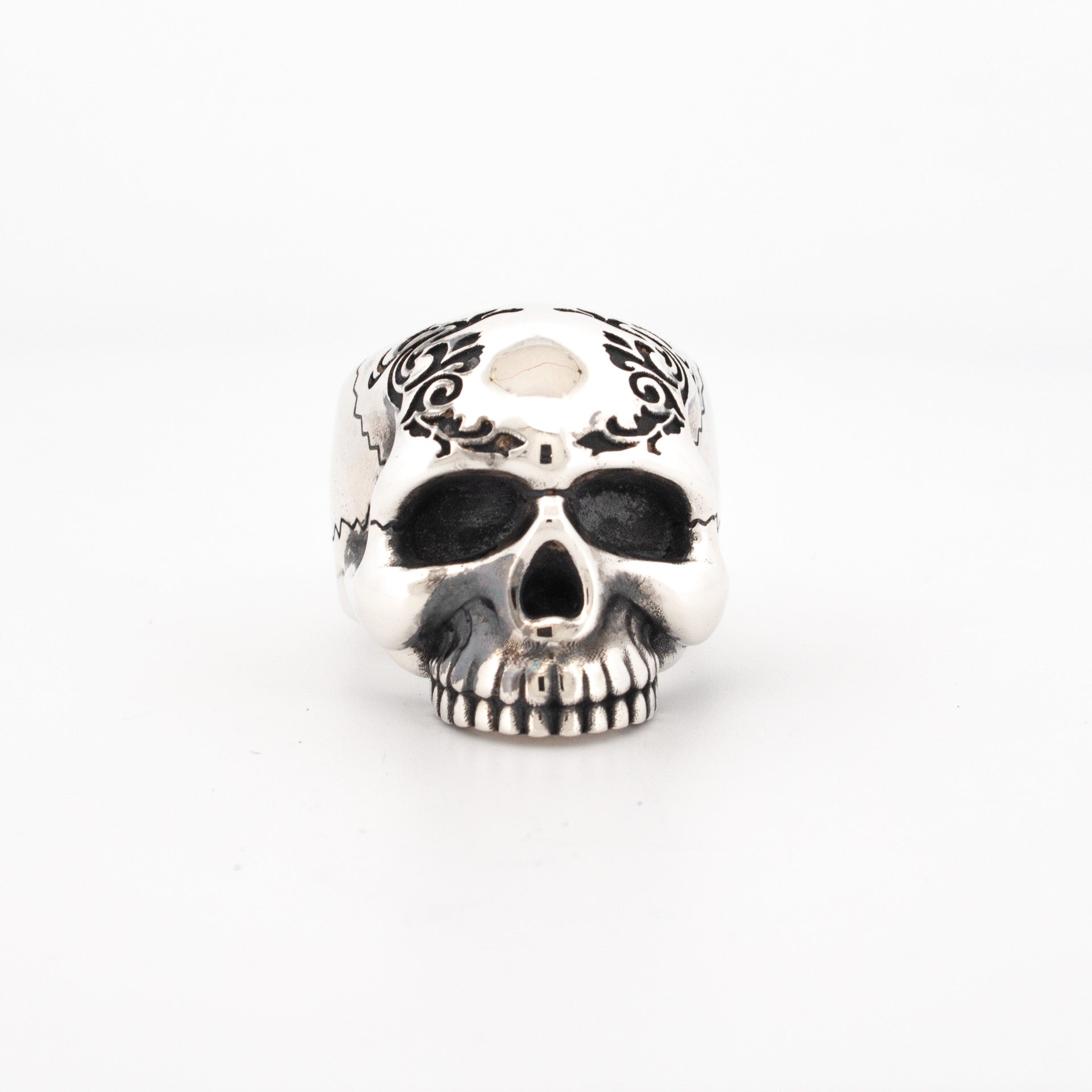 Sterling silver skull ring with black enamel scroll engraving and oxidised eye sockets.