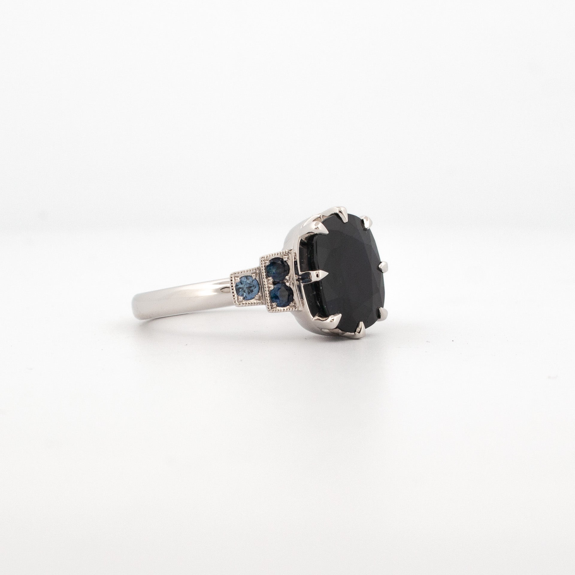 A platinum ring featuring a large central Australian Sapphire with smaller coloured gemstone accents on the shoulders.