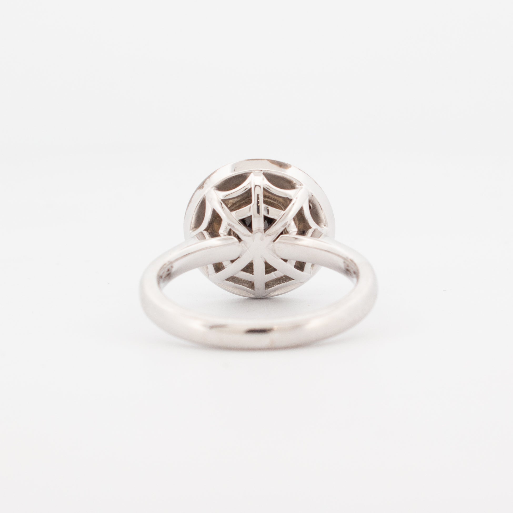 back view of the 9ct white gold double halo engagement ring featuring a round faceted black spinel centre stone, encircled by pavé-set white and black diamonds with hidden spiderweb detailing beneath the setting.