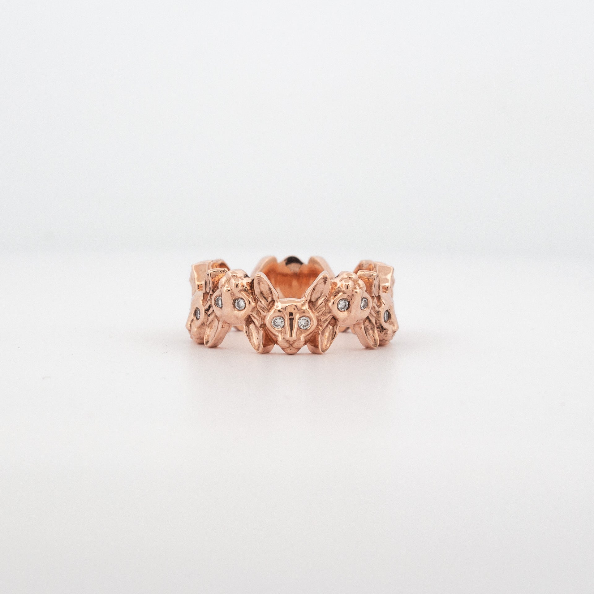 Recycled rose gold ring featuring repeating Cornish Rex cat heads with diamond-set eyes.