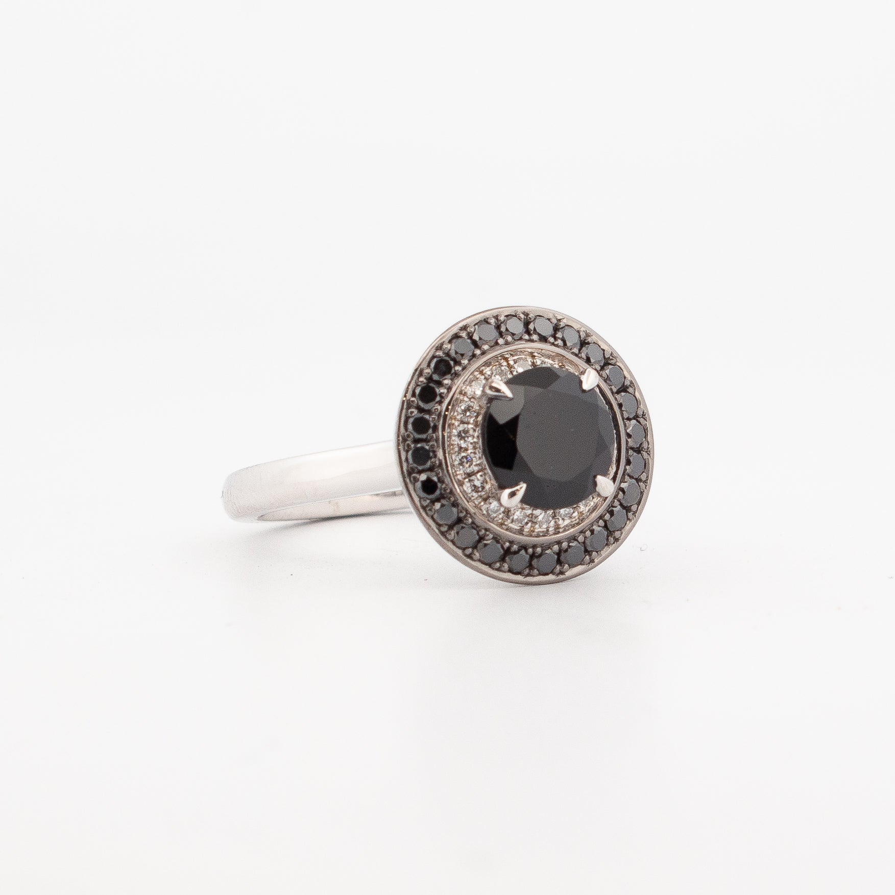 side view of 9ct white gold double halo engagement ring featuring a round faceted black spinel centre stone, encircled by pavé-set white and black diamonds with hidden spiderweb detailing beneath the setting."