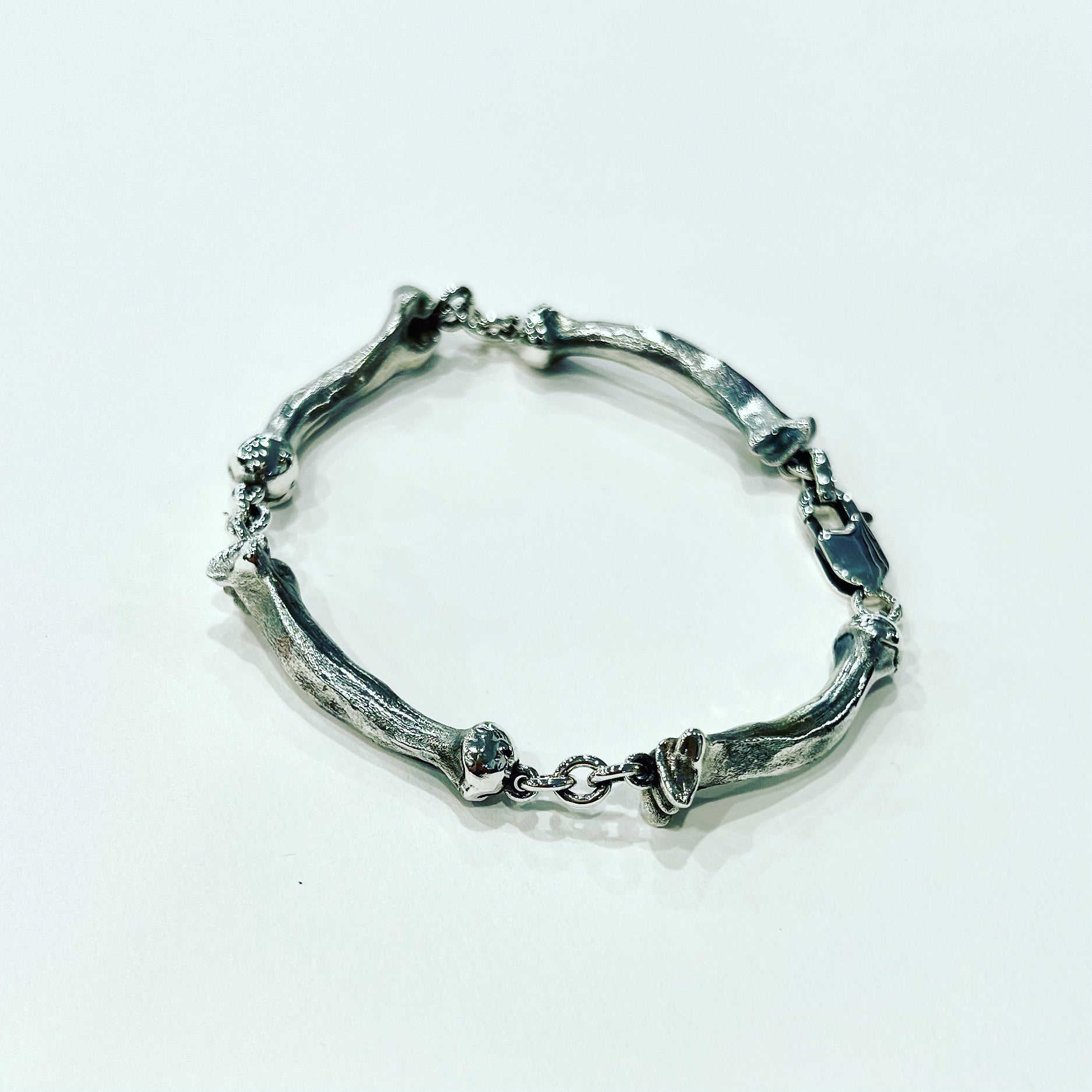 Sterling silver bracelet with four bent femur bone links, anatomical design, textured finish and secure clasp, handmade custom silver jewellery