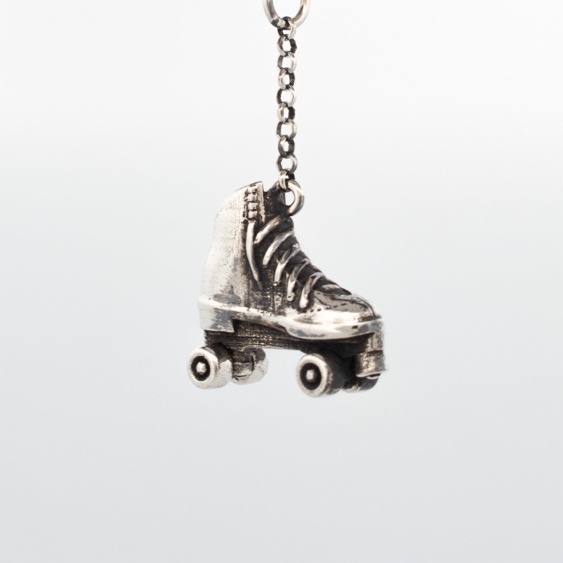 Sterling silver roller skate pendant with detailed laces, boot texture, and free-rolling wheels.
