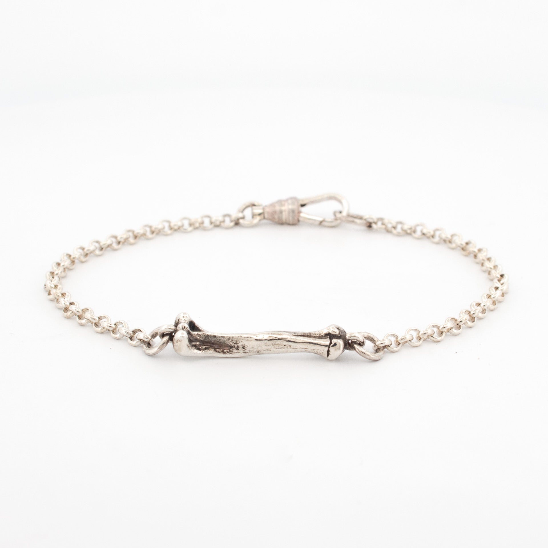 Sterling silver bracelet featuring a sculpted bone link centerpiece with round belcher chain and a hook clasp.