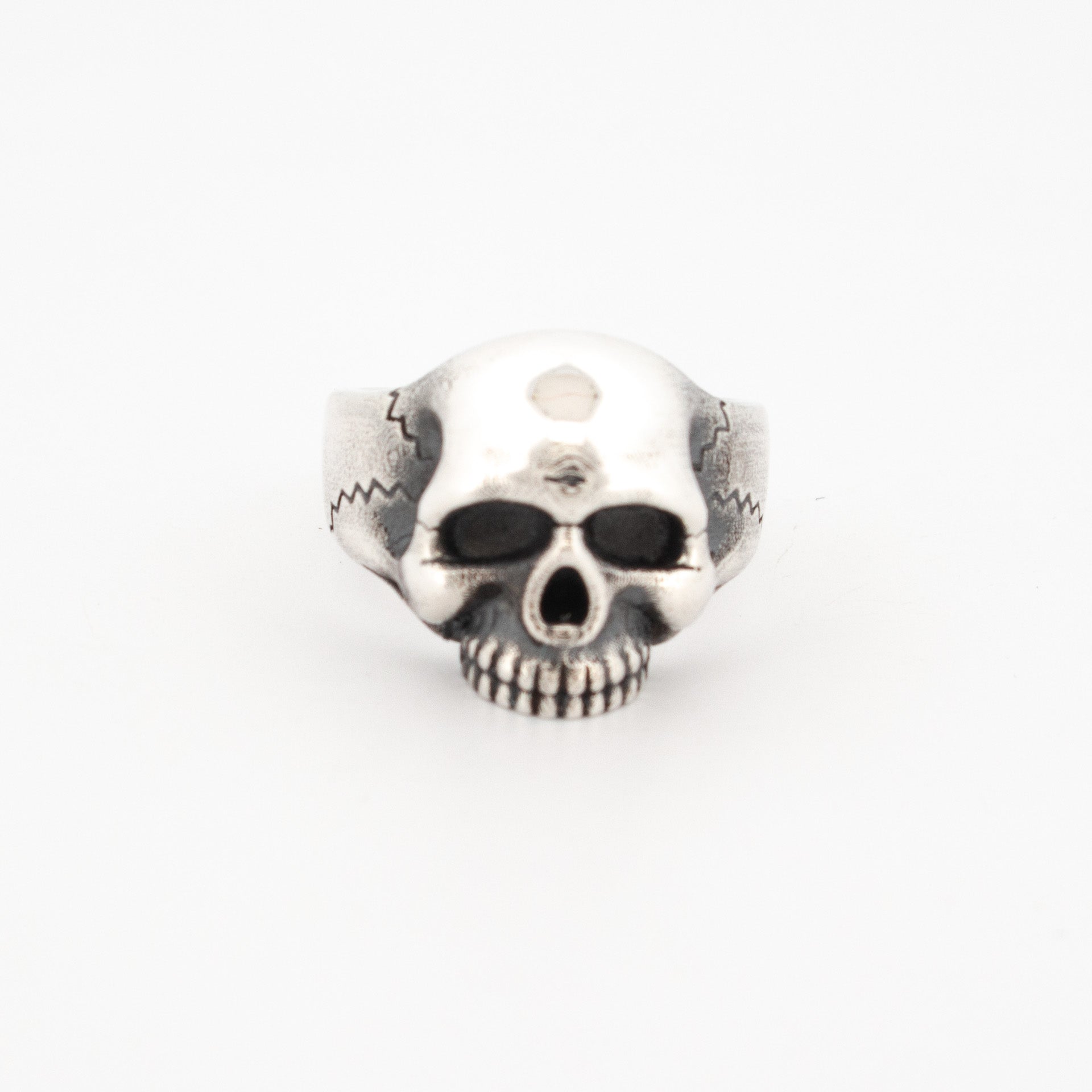 Sterling silver ring sculpted as a full skull with oxidised eye sockets and engraved temple detailing.