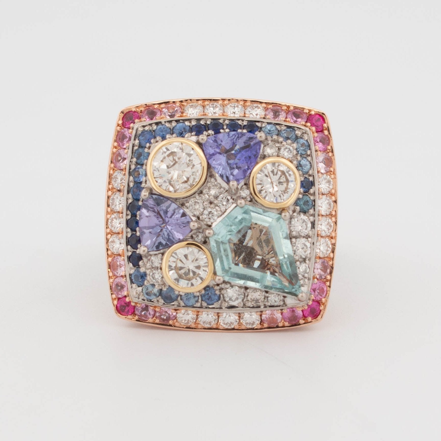 Handmade 18ct rose, white, and yellow gold ring featuring central aquamarine in geometric cut, tanzanite in triangular cuts, round brilliant cut diamonds in yellow gold bezels, and pavé-set colour fade sapphires transitioning from pink to blue.