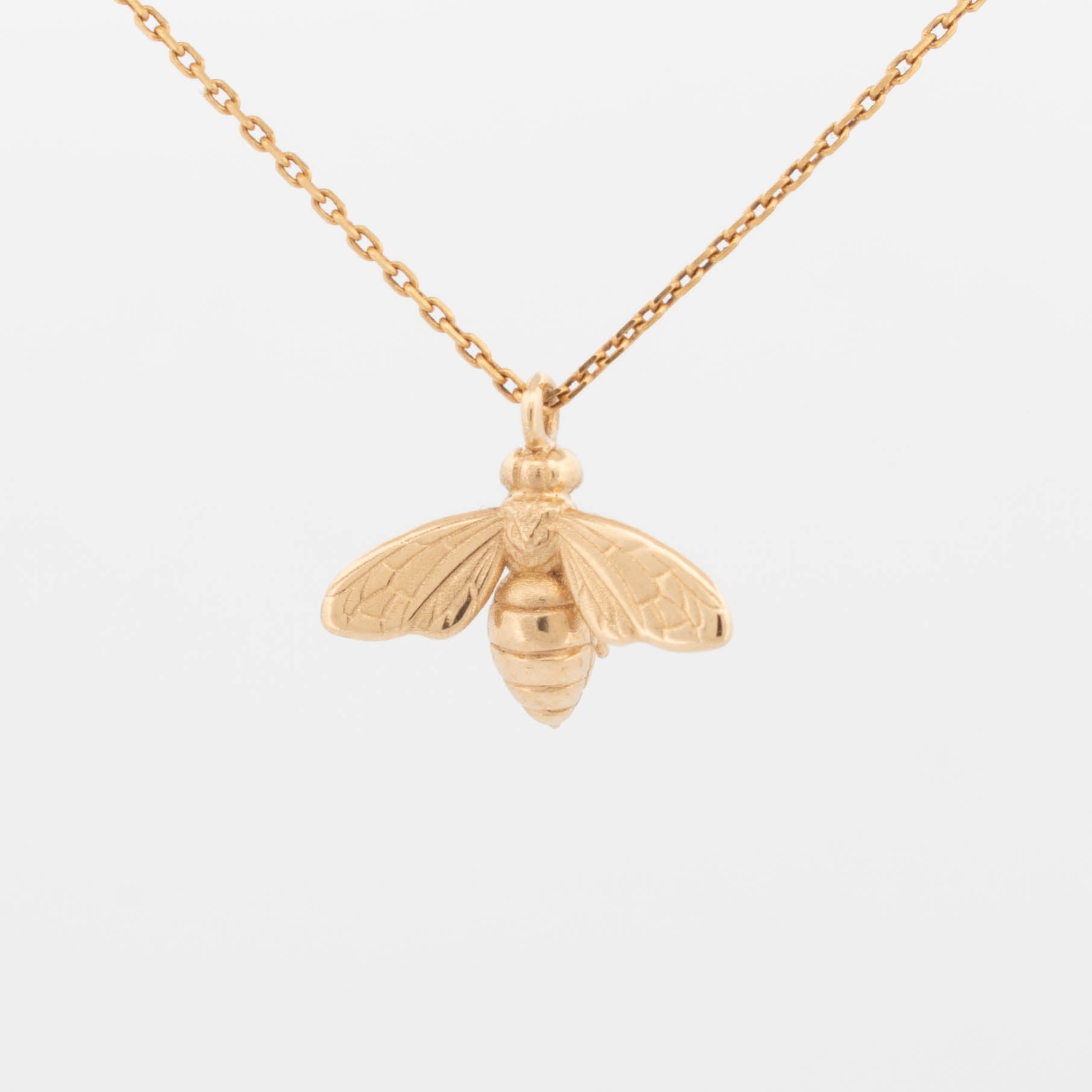 Solid gold bee pendant with fine wing and body detailing, hanging on gold chain, handmade insect necklace